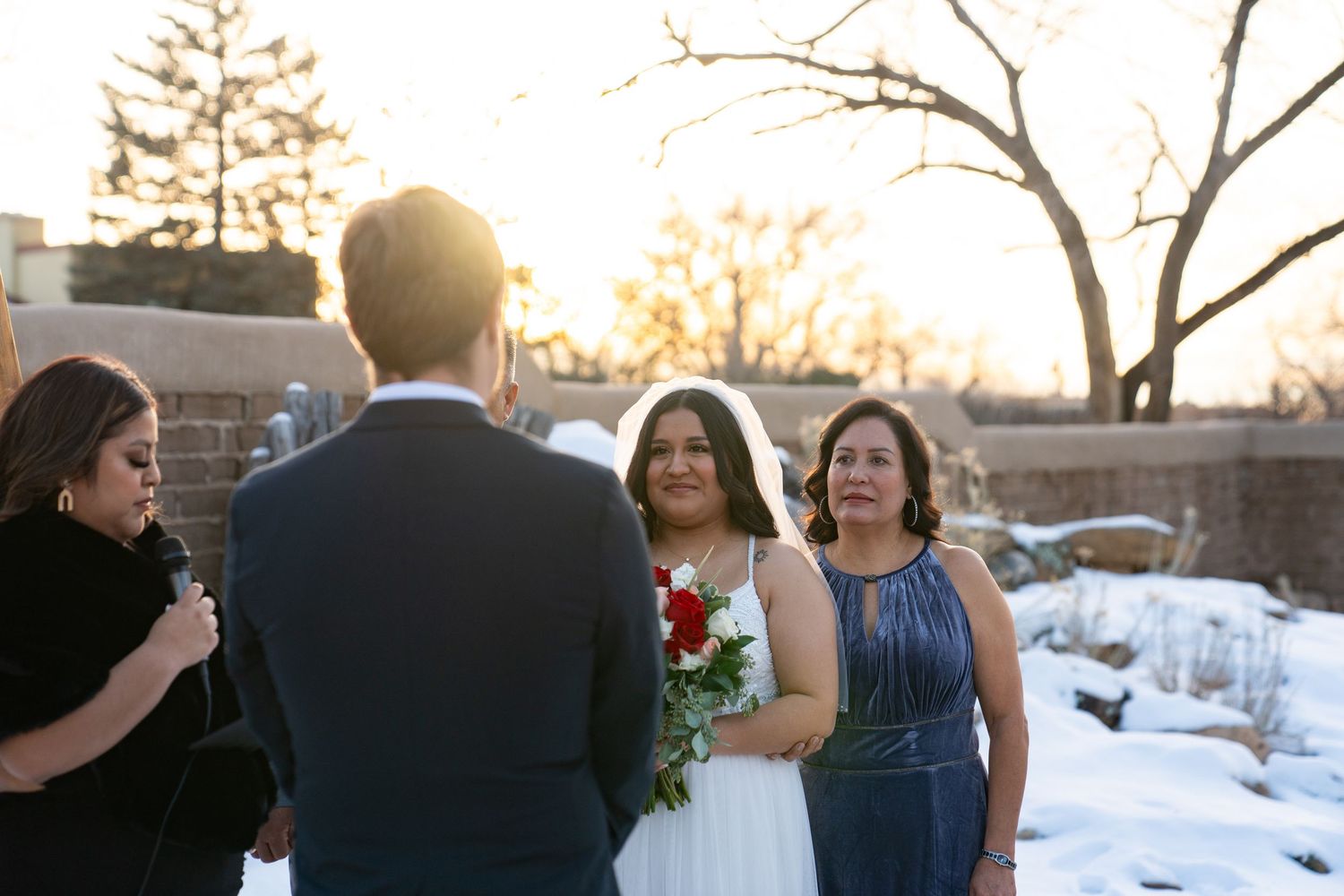 Winter wedding party portraits captured at sunset with snow in the background.