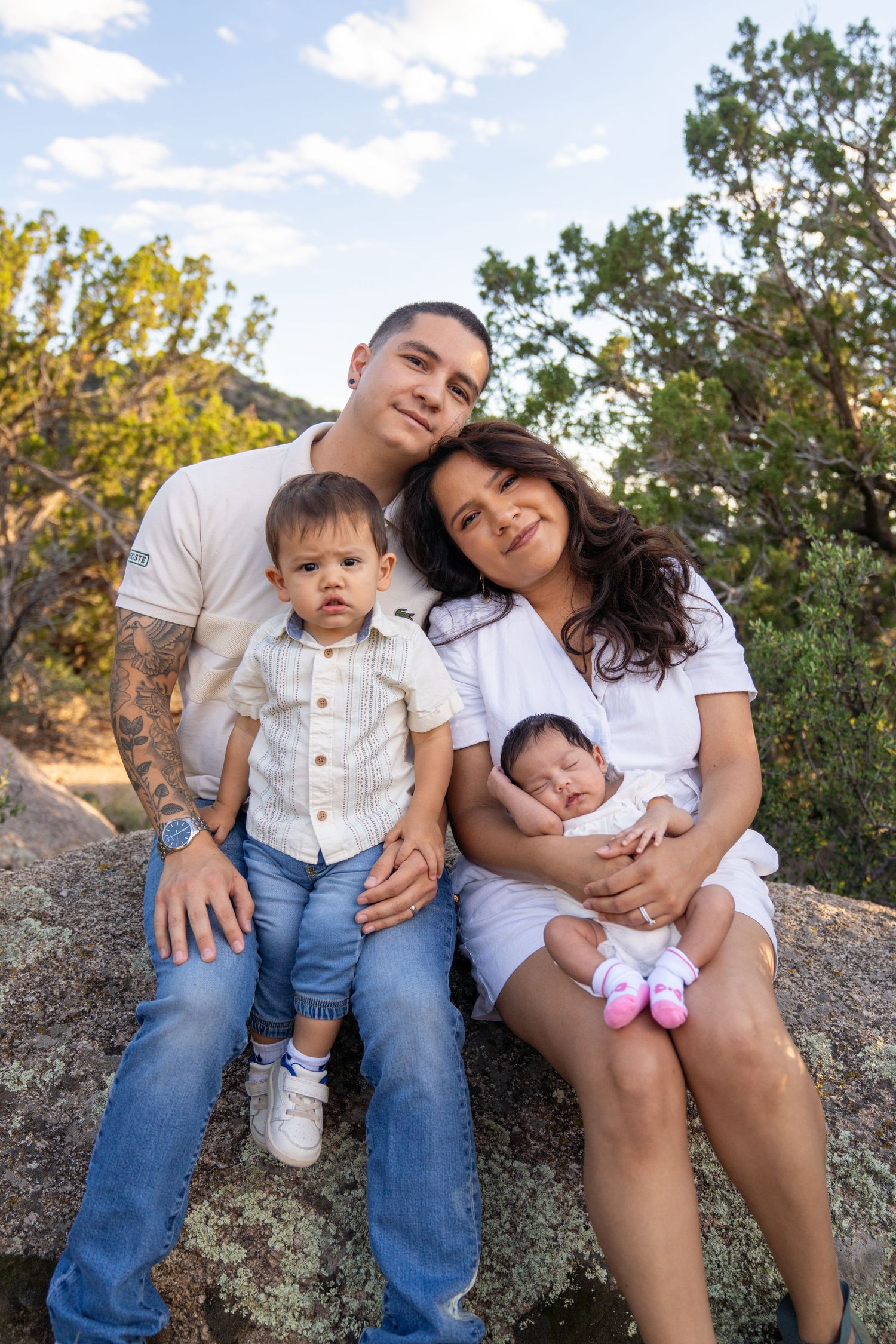 Family sits together on rocks in a natural outdoor setting.