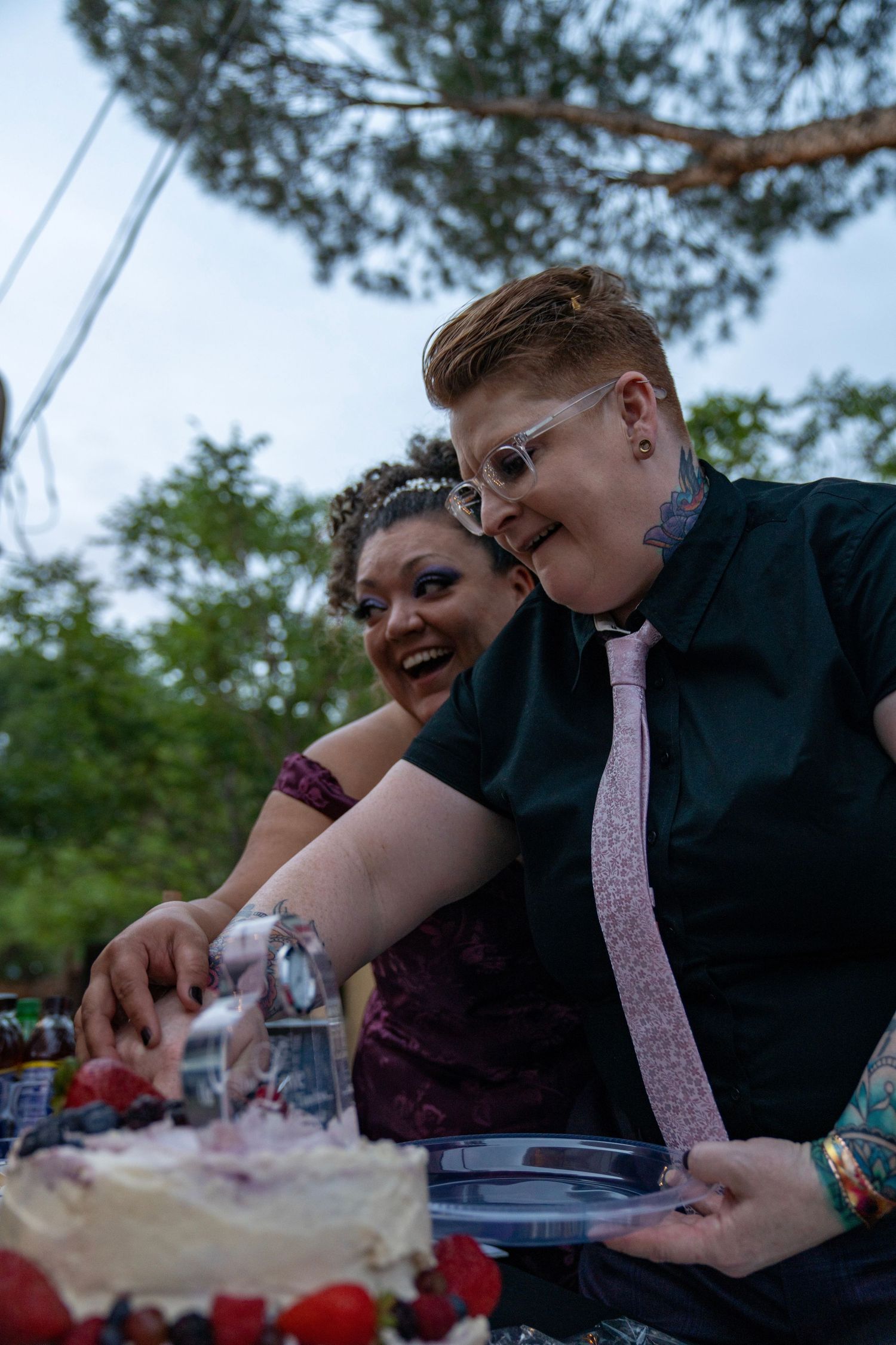 Two people lean over a table outdoors while examining something together in a series of connected photos.