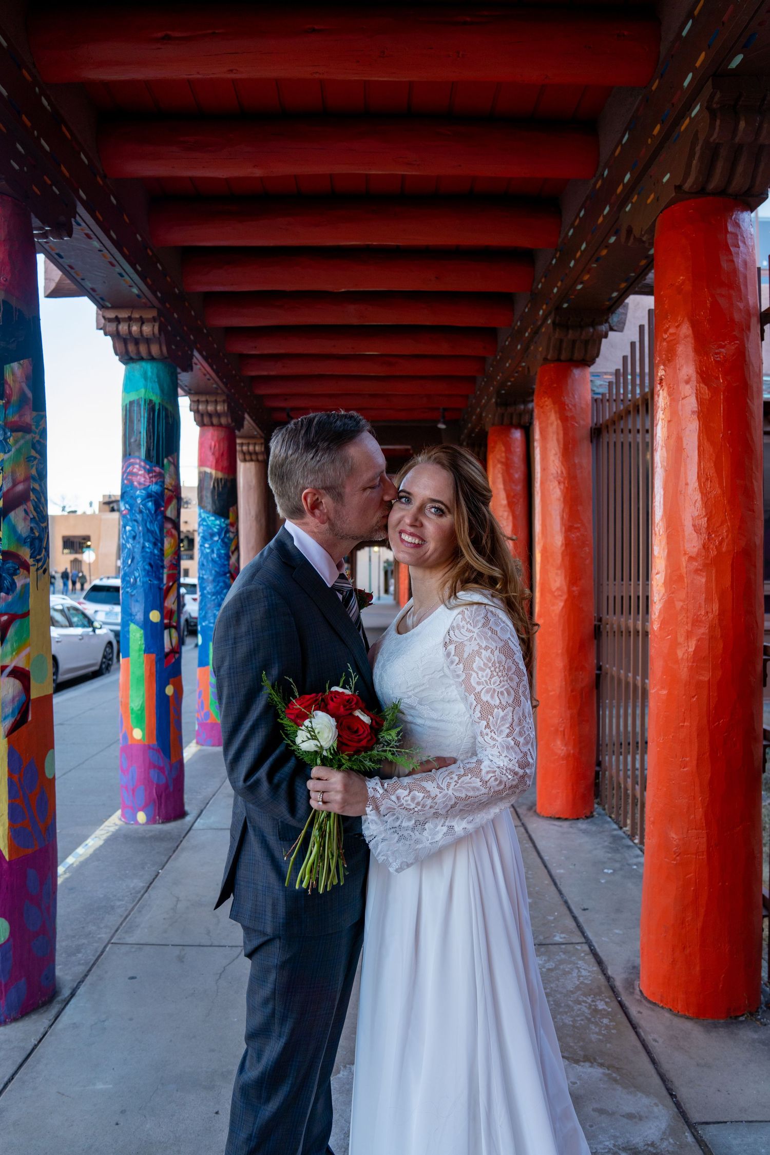 A wedding portrait under colorful painted columns with red and turquoise architectural details.