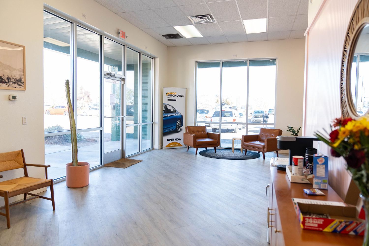 Modern medical office waiting area with large windows, white walls, and wooden benches arranged along the perimeter.