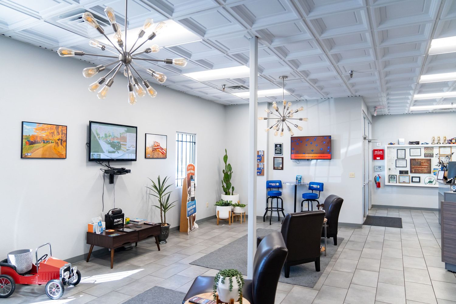 Modern office interior with white walls, tiled floors, and artwork displays along a long hallway.