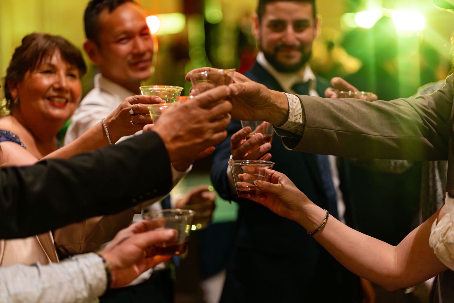 Wedding guests raising glasses in a celebratory toast at a reception party.