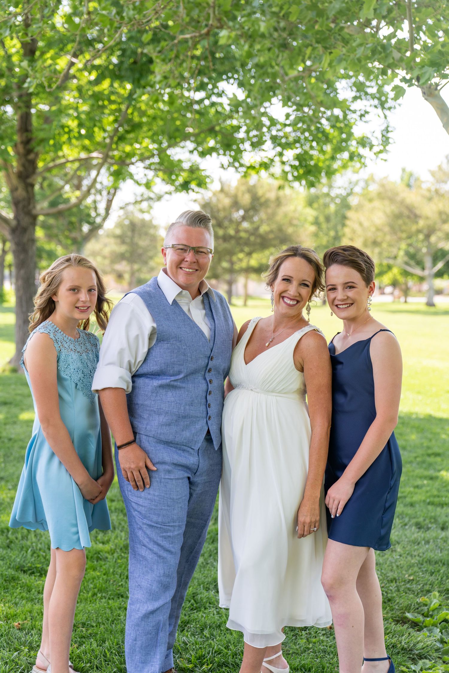 A group in blue and white outfits poses together on a grassy lawn during a sunny outdoor gathering.