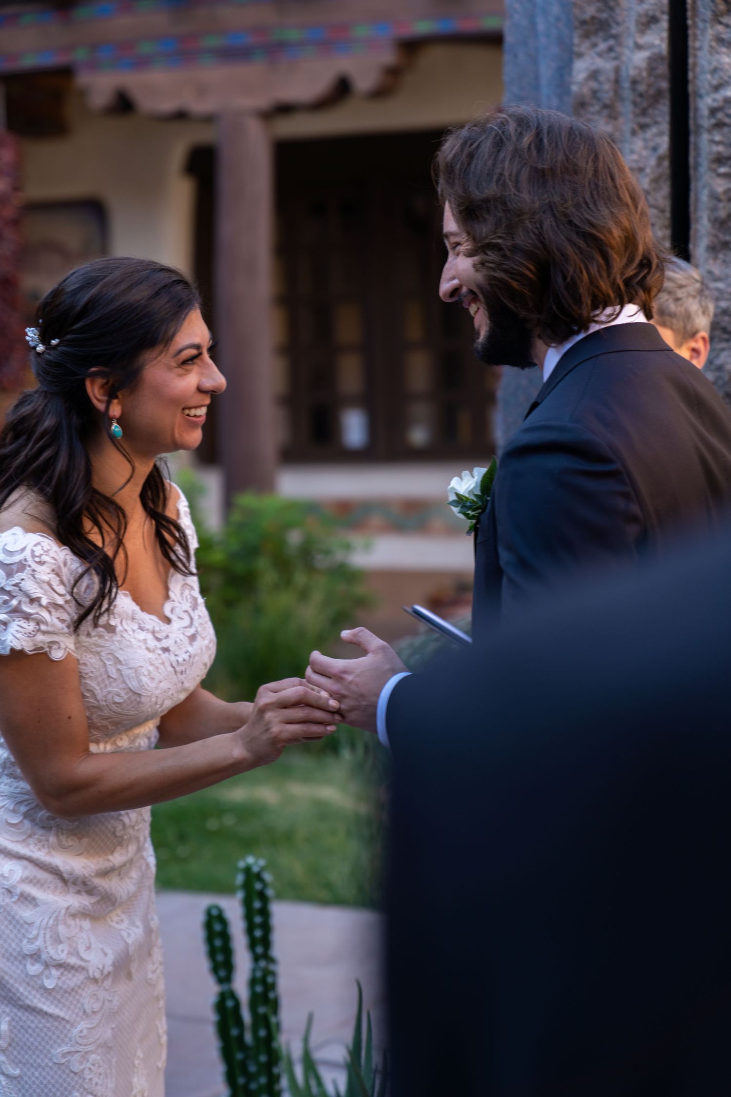 A couple shares a joyful moment during their wedding ceremony in an outdoor garden setting.
