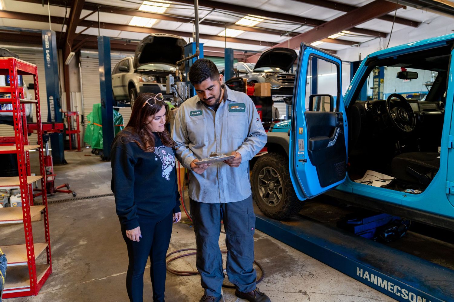 Auto repair shop interior showing multiple vehicle lifts and mechanical equipment in a spacious warehouse setting.