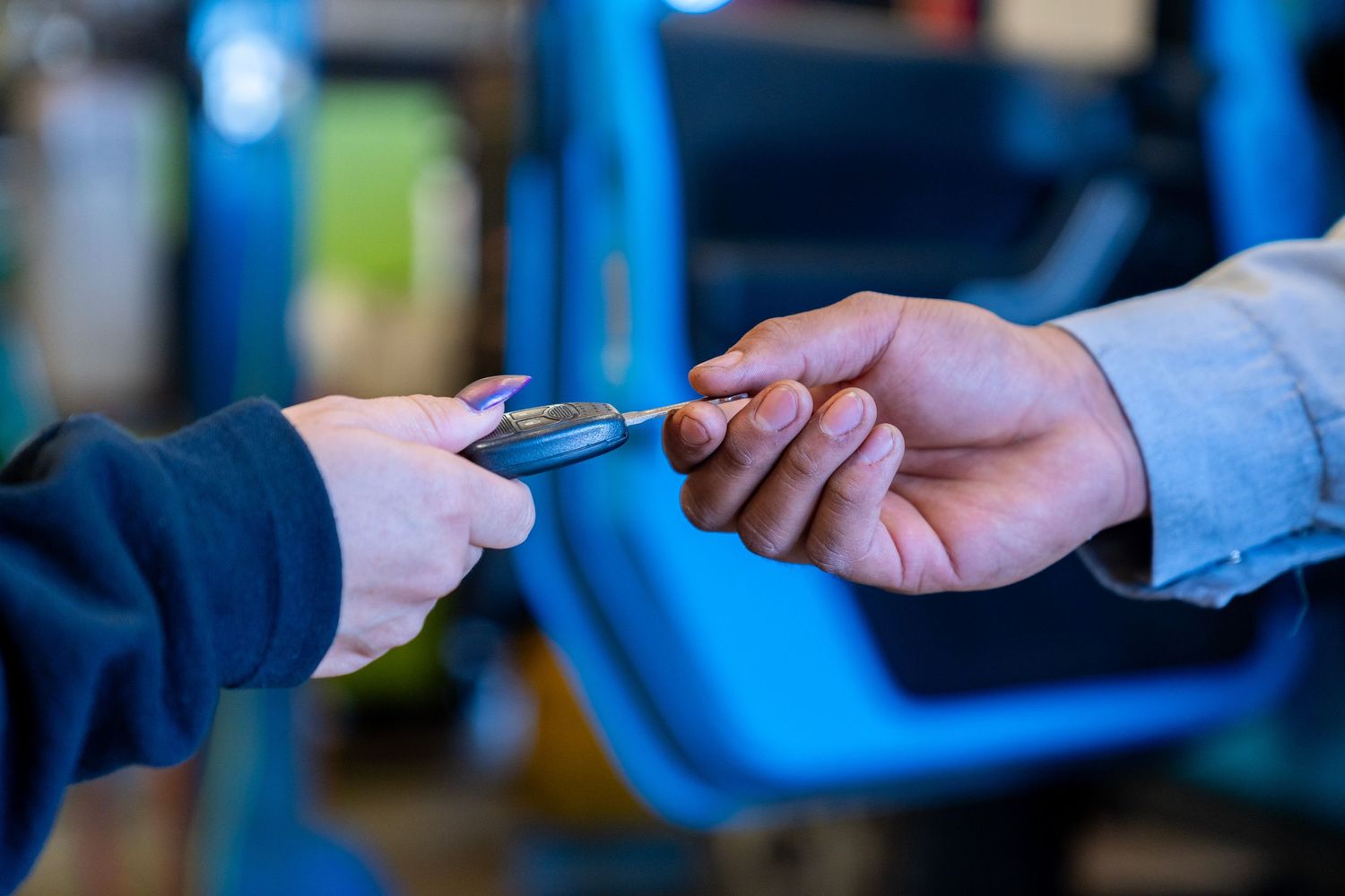Two hands exchanging a blue credit card during a payment transaction in a retail setting.