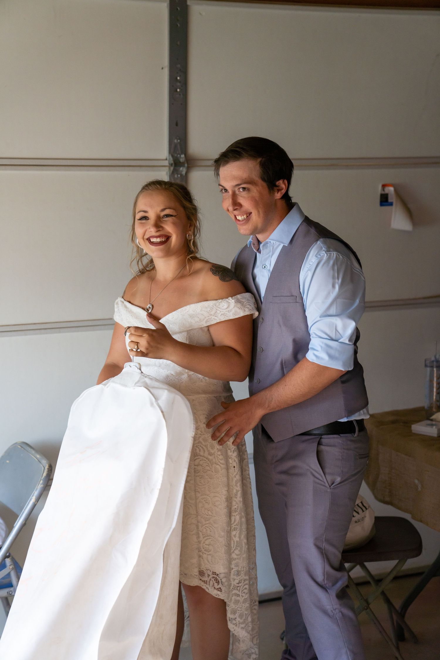 A couple shares a playful moment during a wedding photo session in a light-filled room.