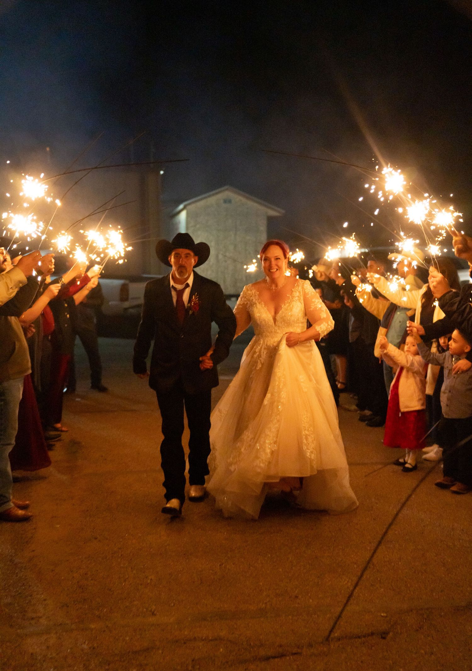 Wedding guests hold sparklers in a nighttime celebration creating a magical light display.