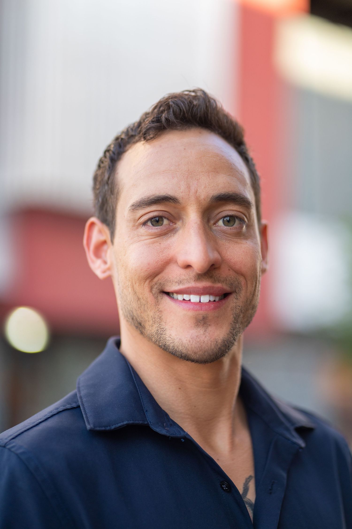 Close-up professional headshot of a person in a navy shirt with a warm smile.