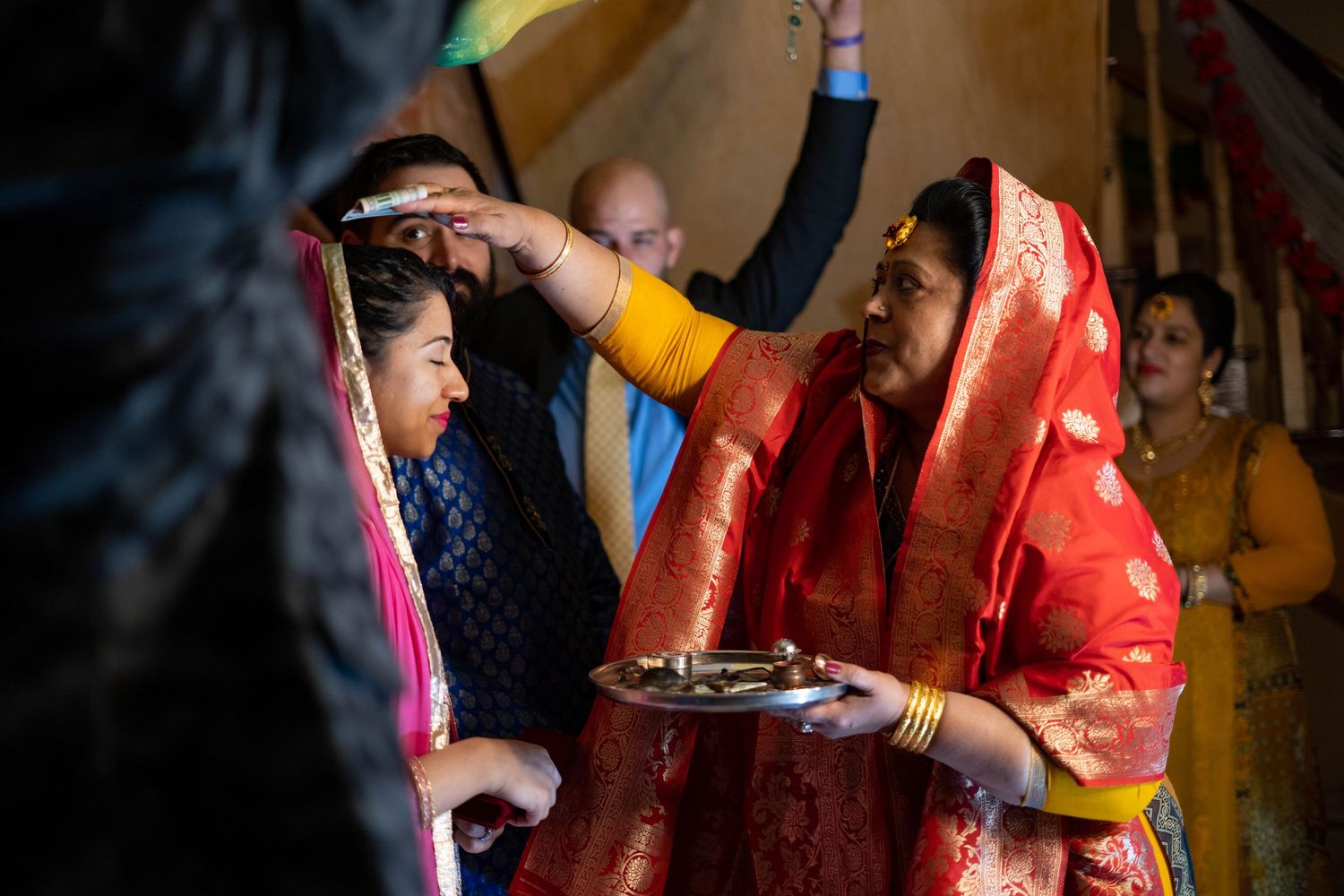 A traditional Indian wedding ceremony shows hands performing rituals with oil lamps and sacred items during a marriage celebration.