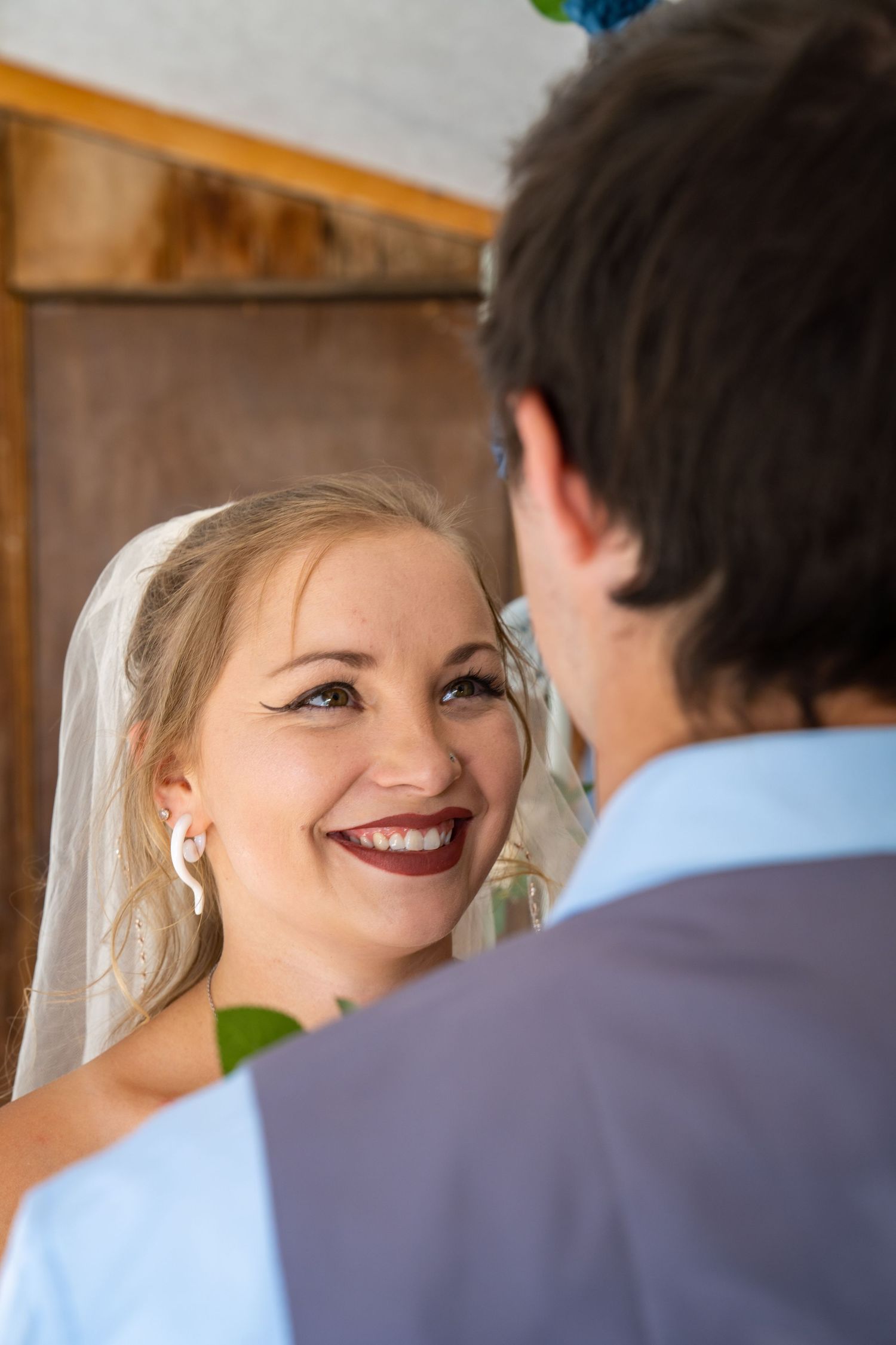 Couple shares intimate moment during wedding ceremony in wooden barn setting.