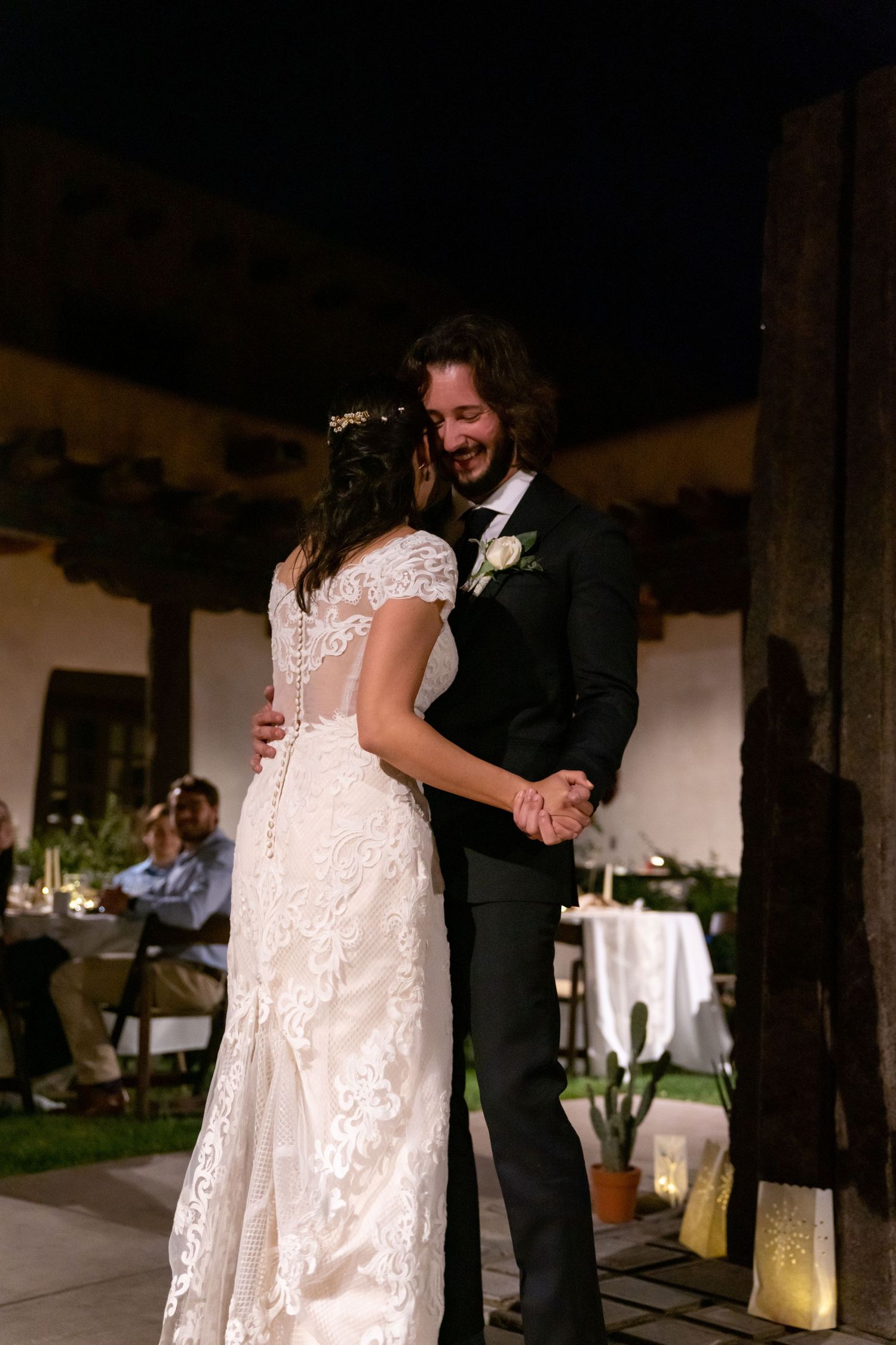 A couple dances together during their wedding reception under covered outdoor patio space.