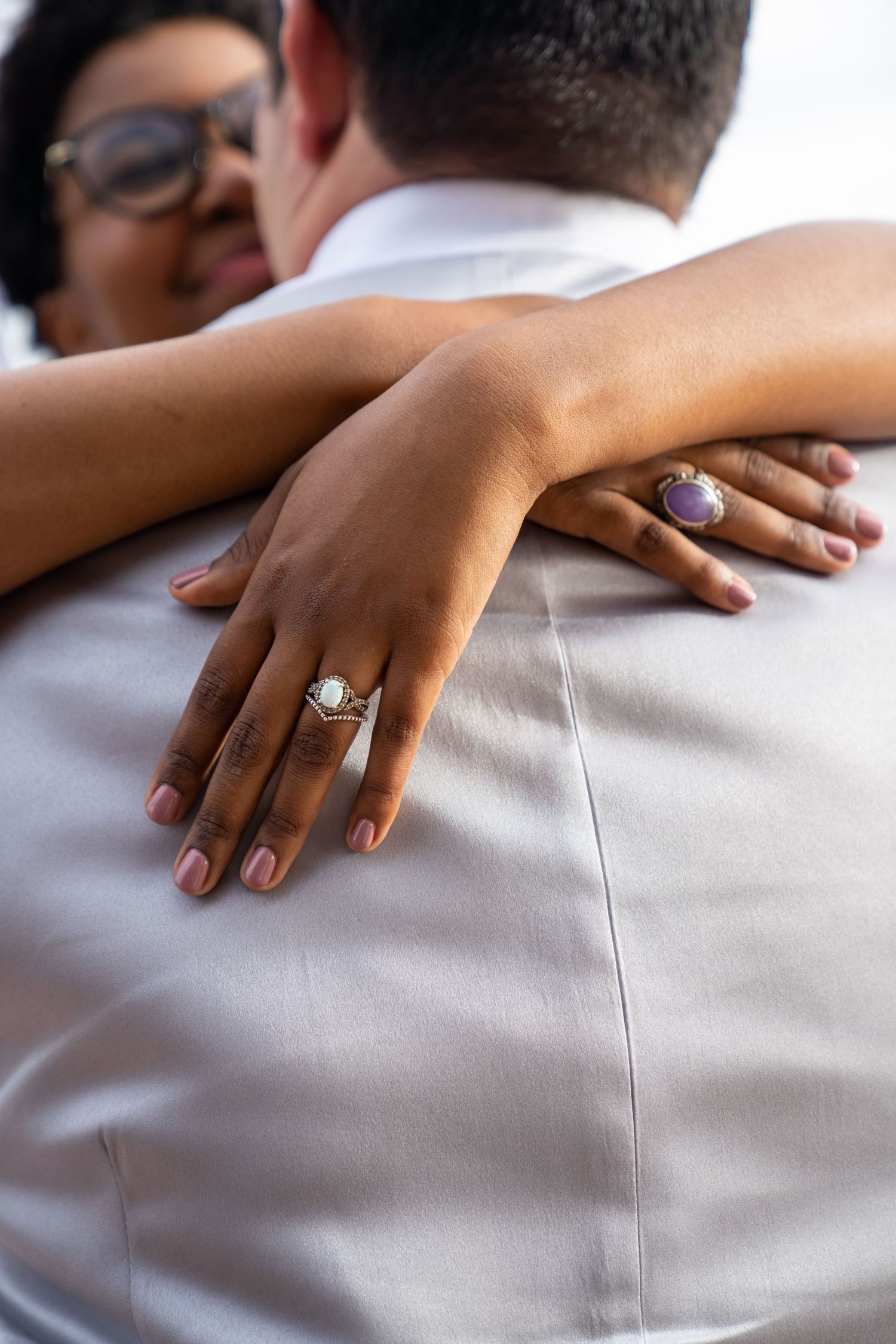 Close-up shots of a bride's hand with engagement ring resting on light gray fabric.