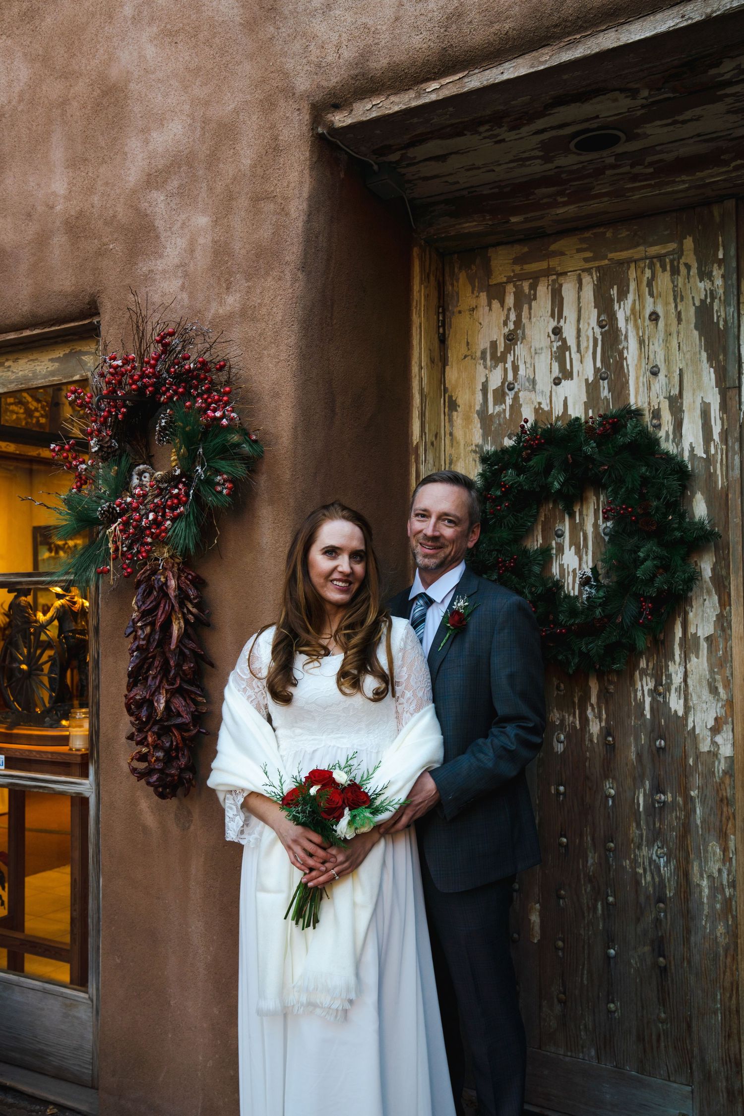 A series of intimate wedding portraits against a rustic adobe wall with holiday decorations and wreaths.