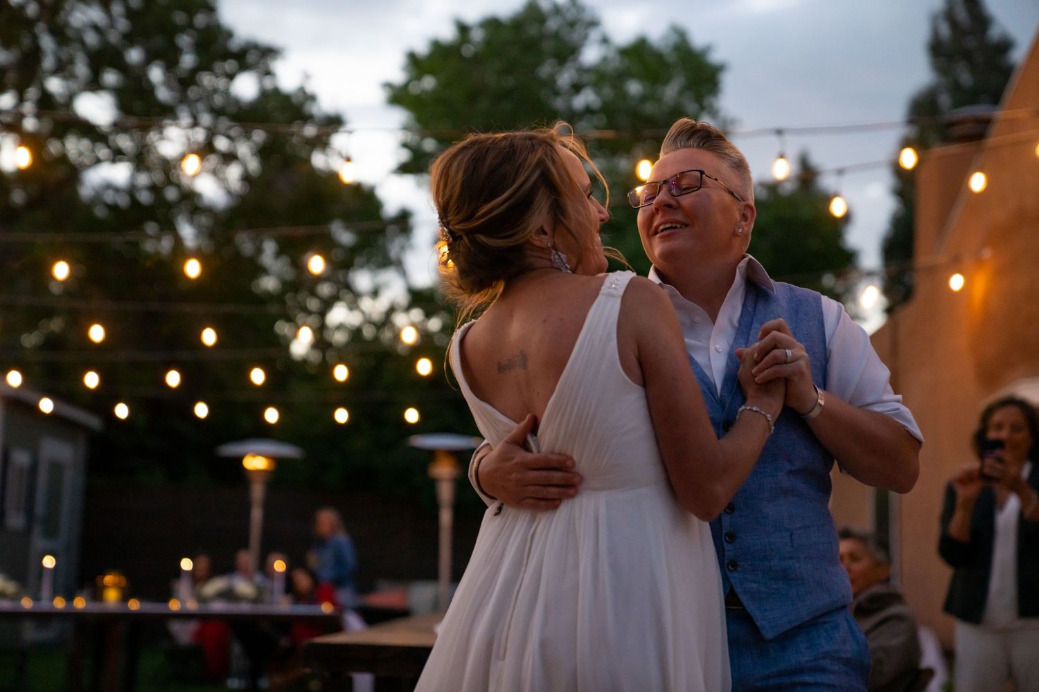Couples dancing together at an outdoor evening wedding reception with string lights overhead.