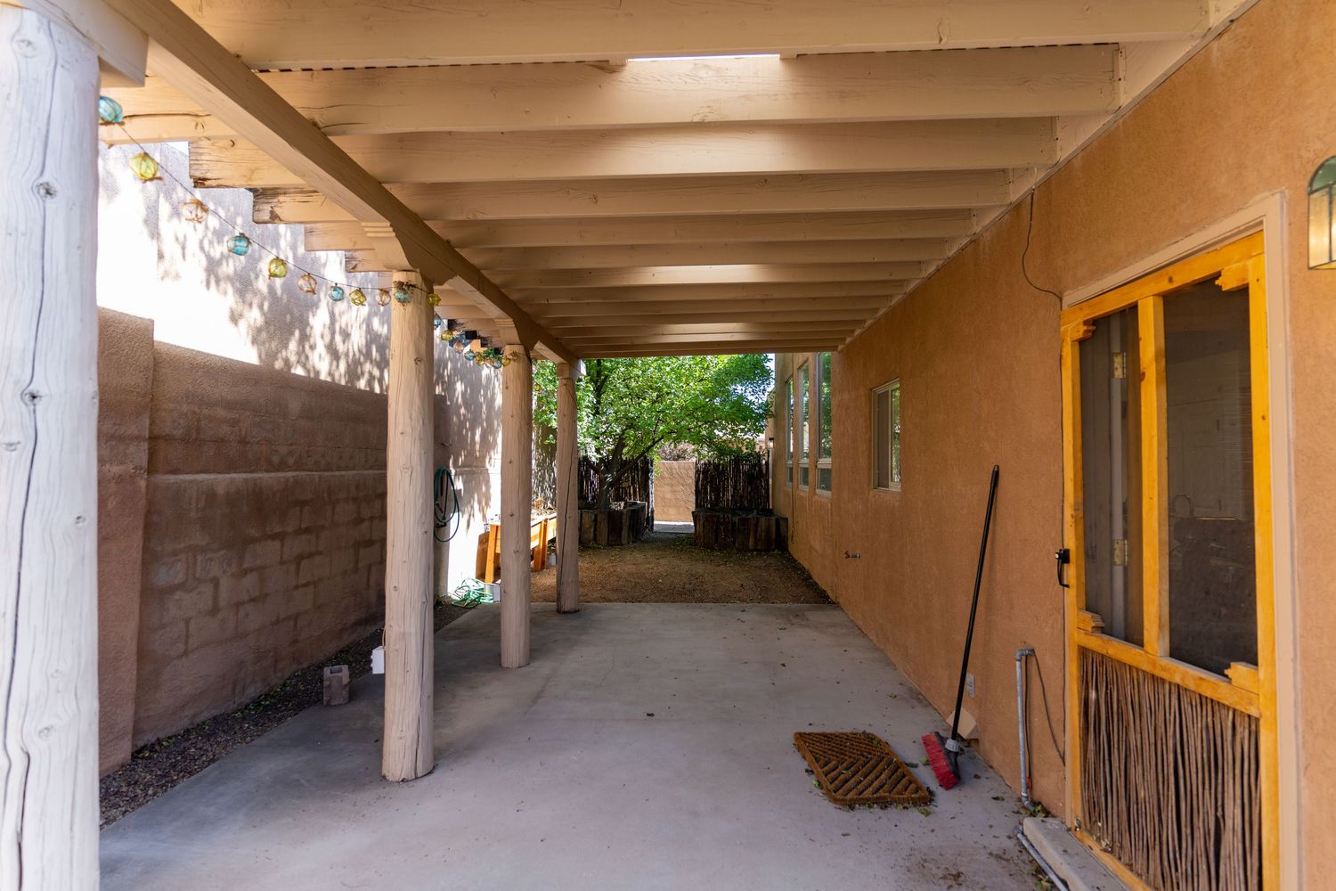 Long covered walkway with exposed beams and concrete walls extends down a corridor with natural lighting.