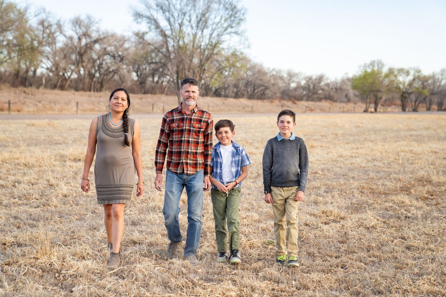 Family walking together through a dry autumn field on a sunny day.