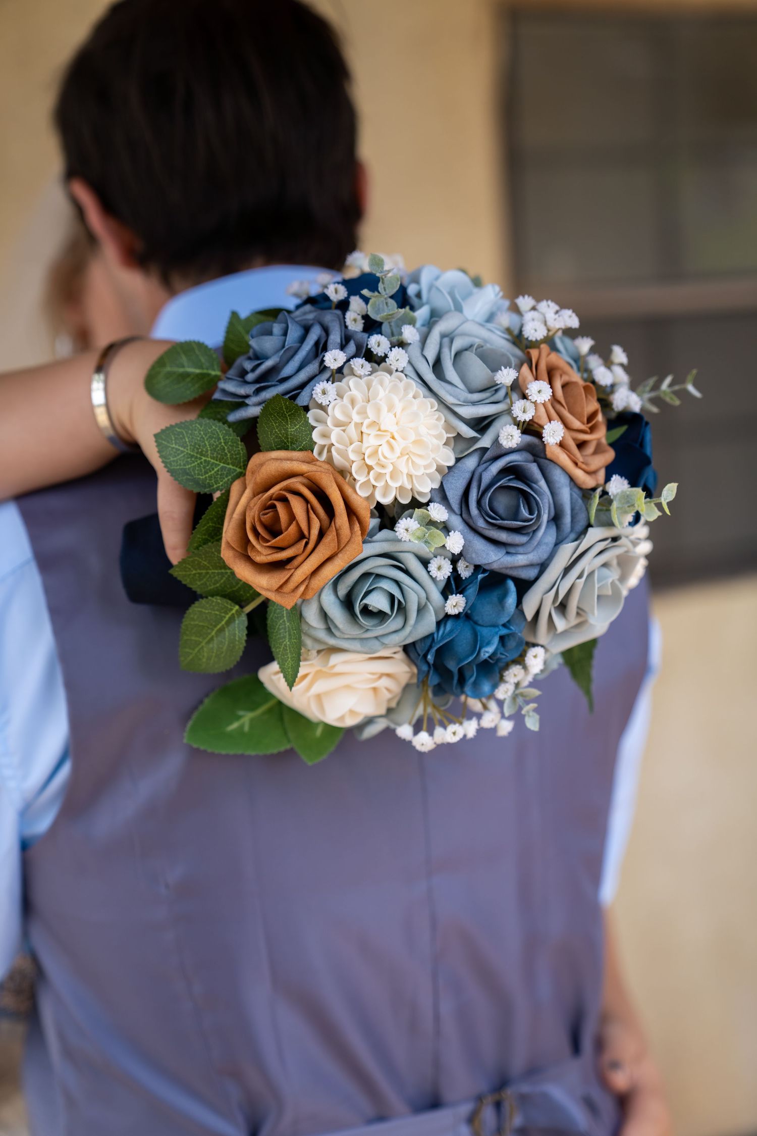 Wedding party members wearing gray suits adorned with coordinating blue and copper floral boutonnieres.