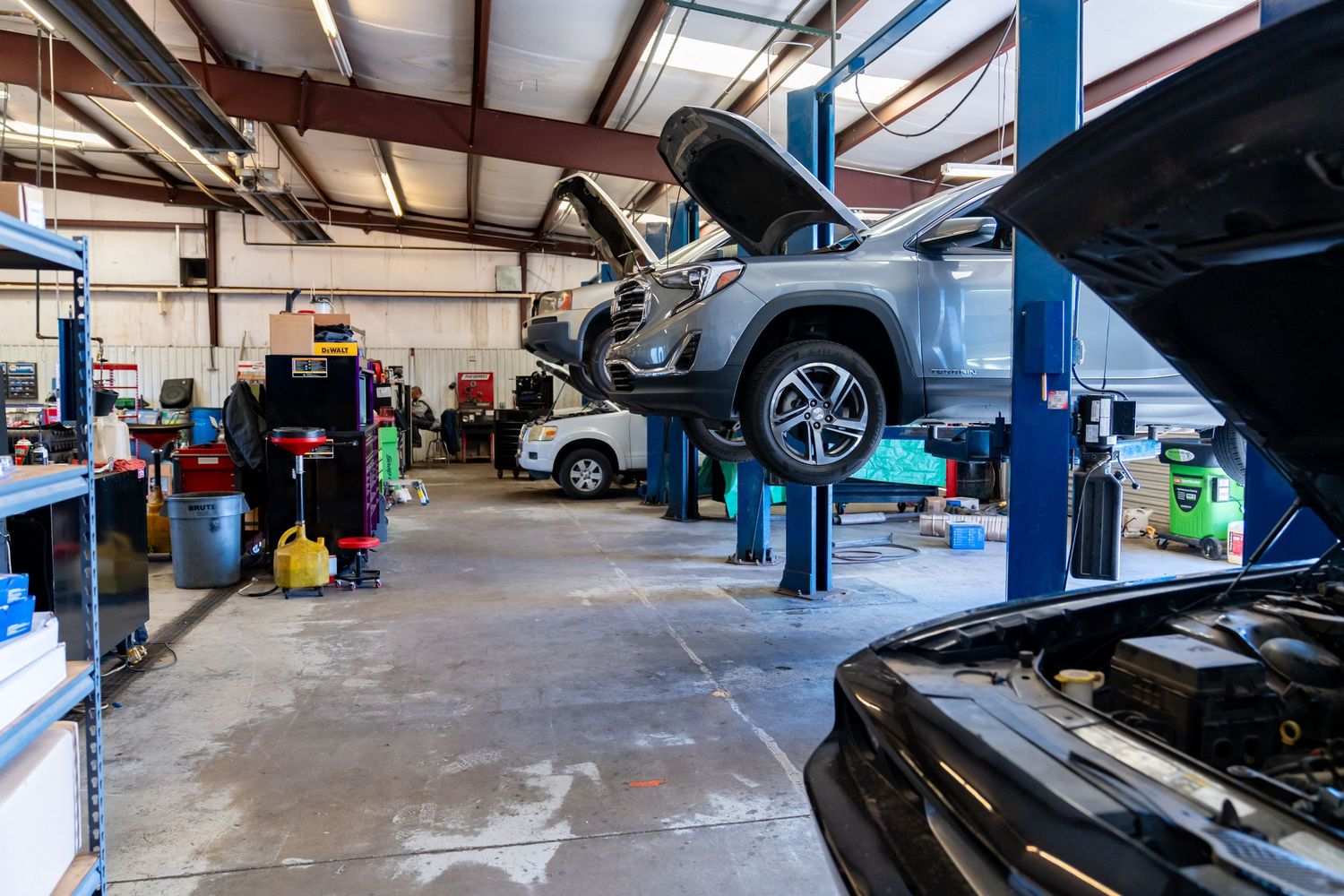 Auto repair shop interior with multiple cars on lifts and mechanics working in a professional service garage.