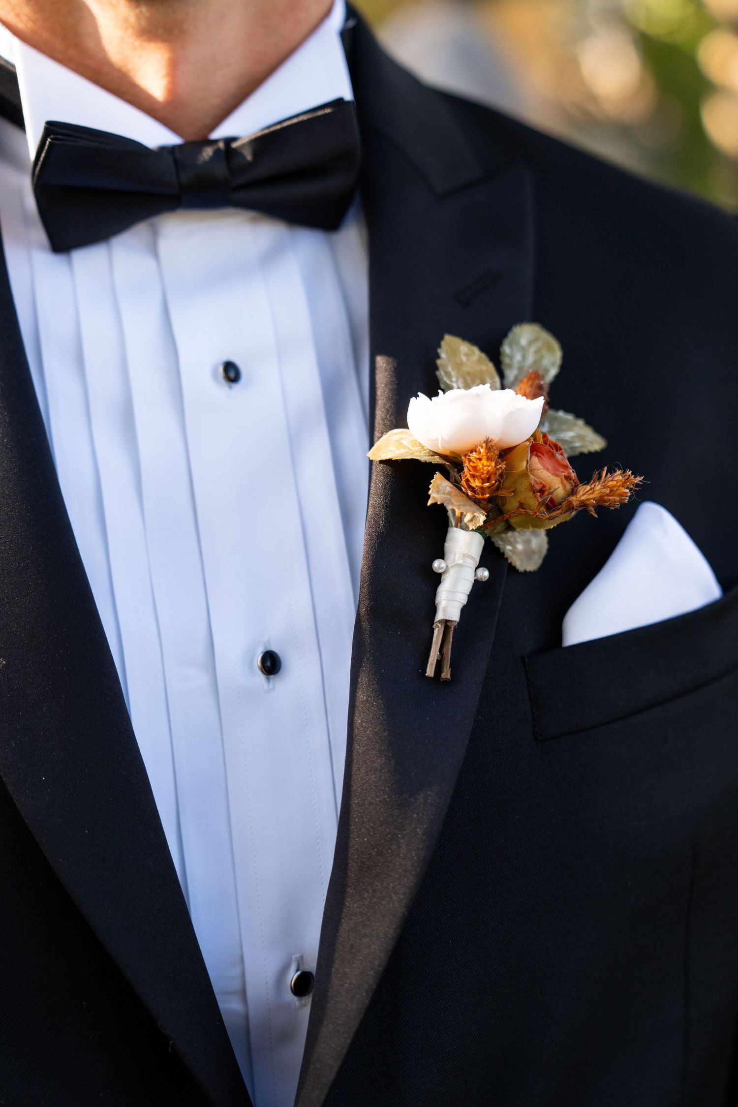 Close-up detail of a classic black tuxedo with fall-colored boutonniere.
