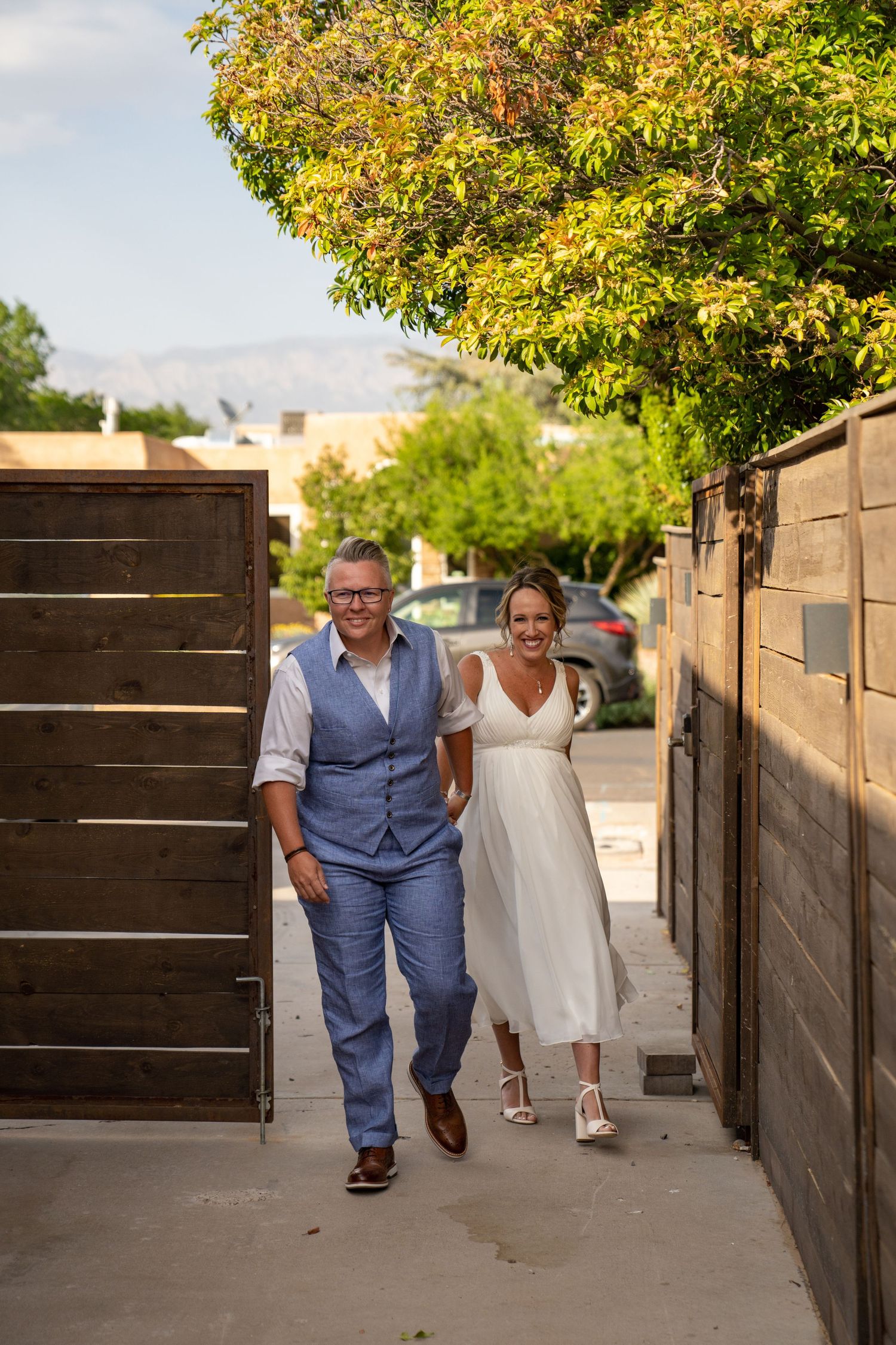 People walking along a wooden fence path on a sunny autumn day.