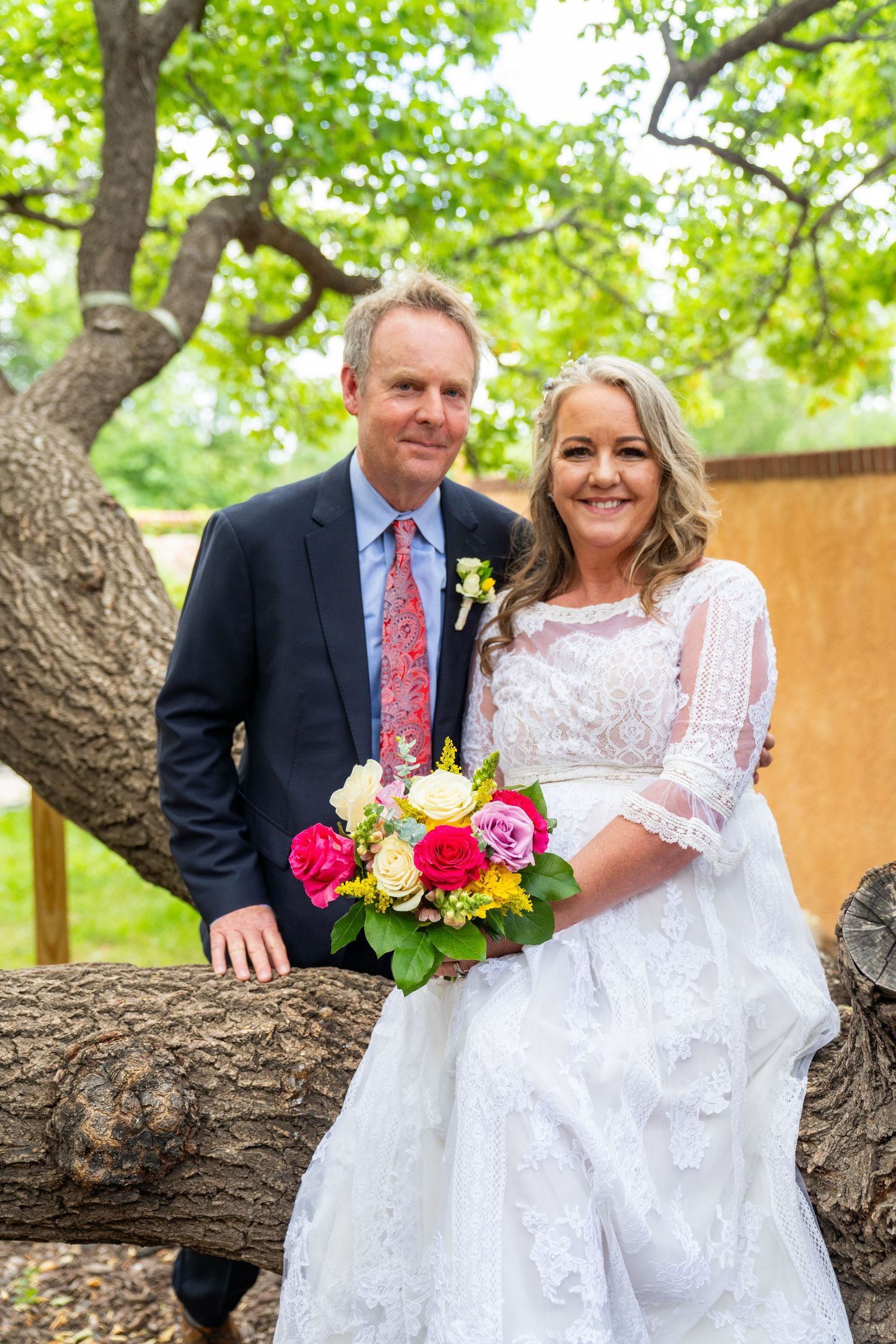 Couple poses for wedding photos against a natural backdrop with trees and greenery.