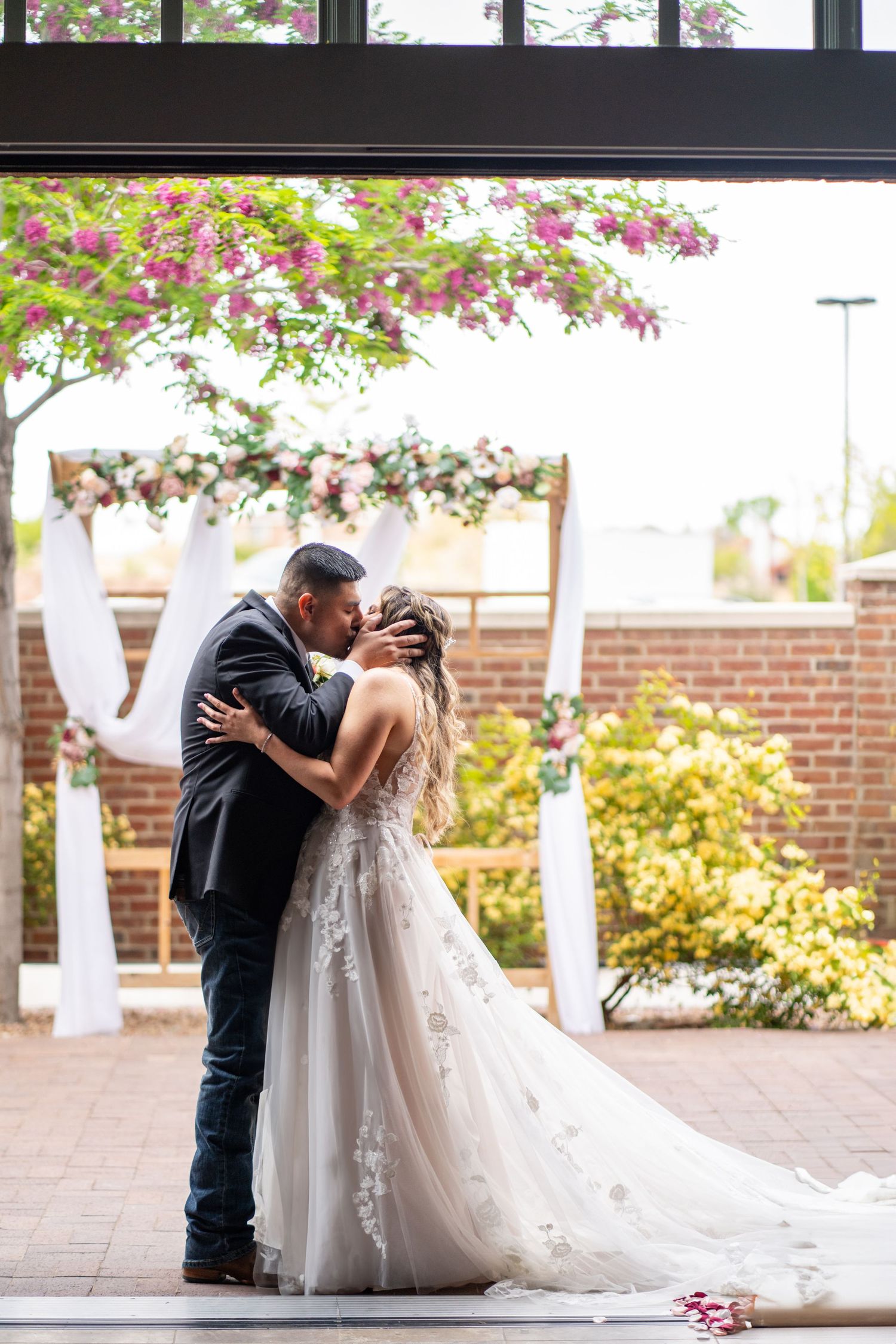 Romantic wedding portraits captured in front of a brick building with floral decor.