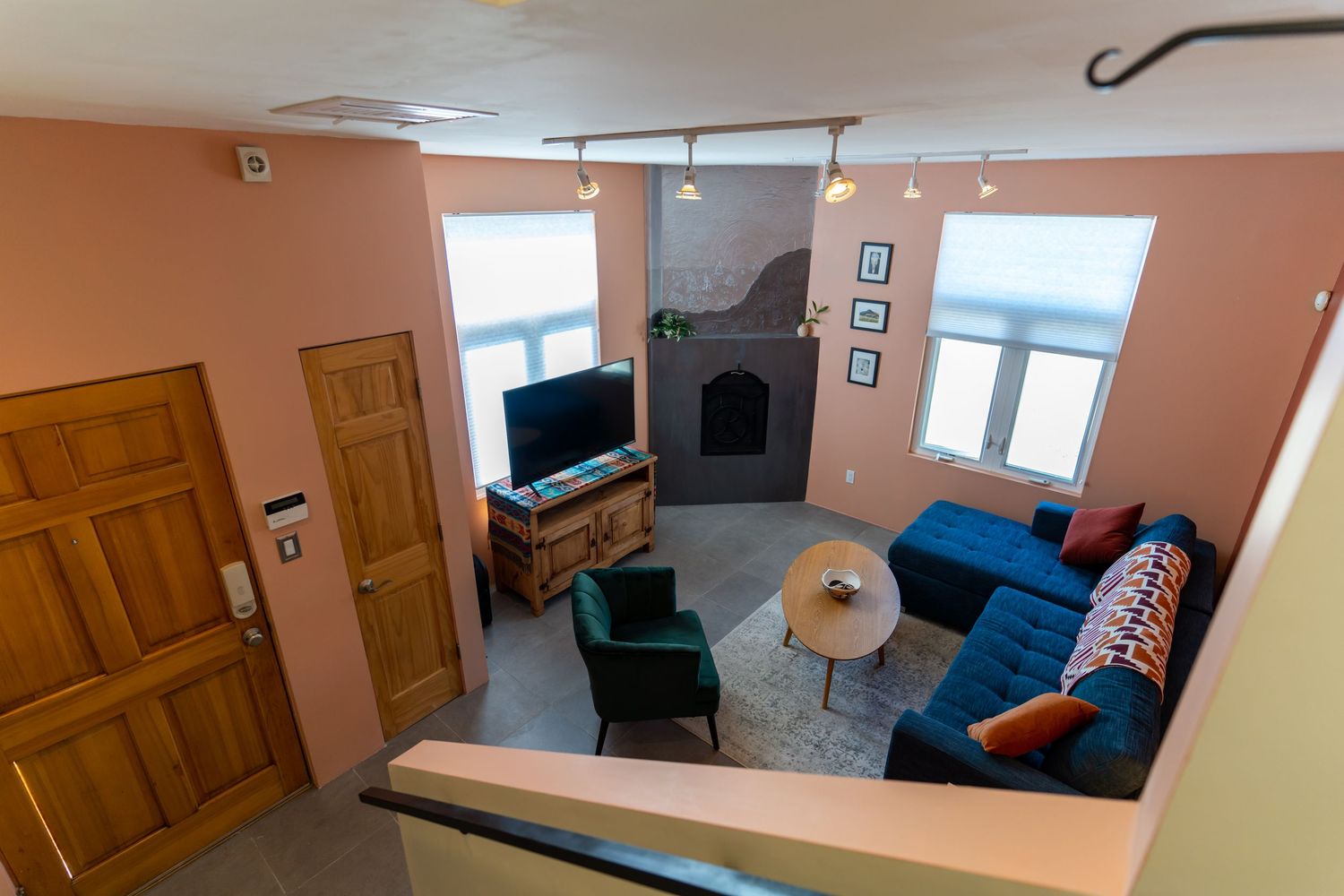 Elevated view of a living room with peach walls, blue sofa, and corner fireplace showing wooden doors and windows.