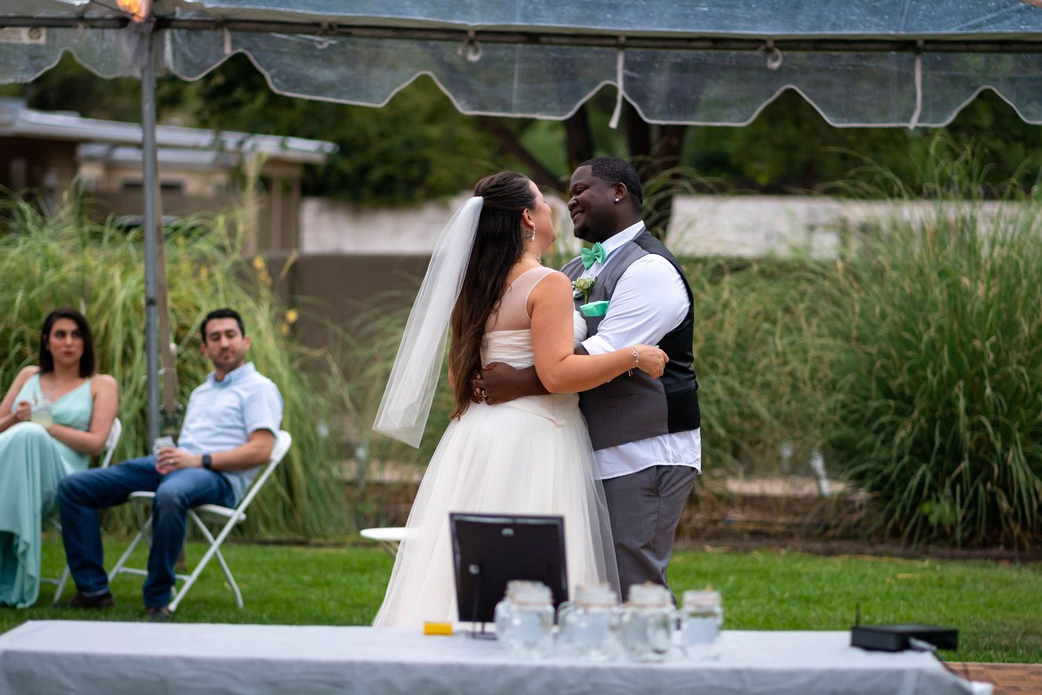 Wedding guests enjoy outdoor reception with drinks and conversation in a scenic garden setting.