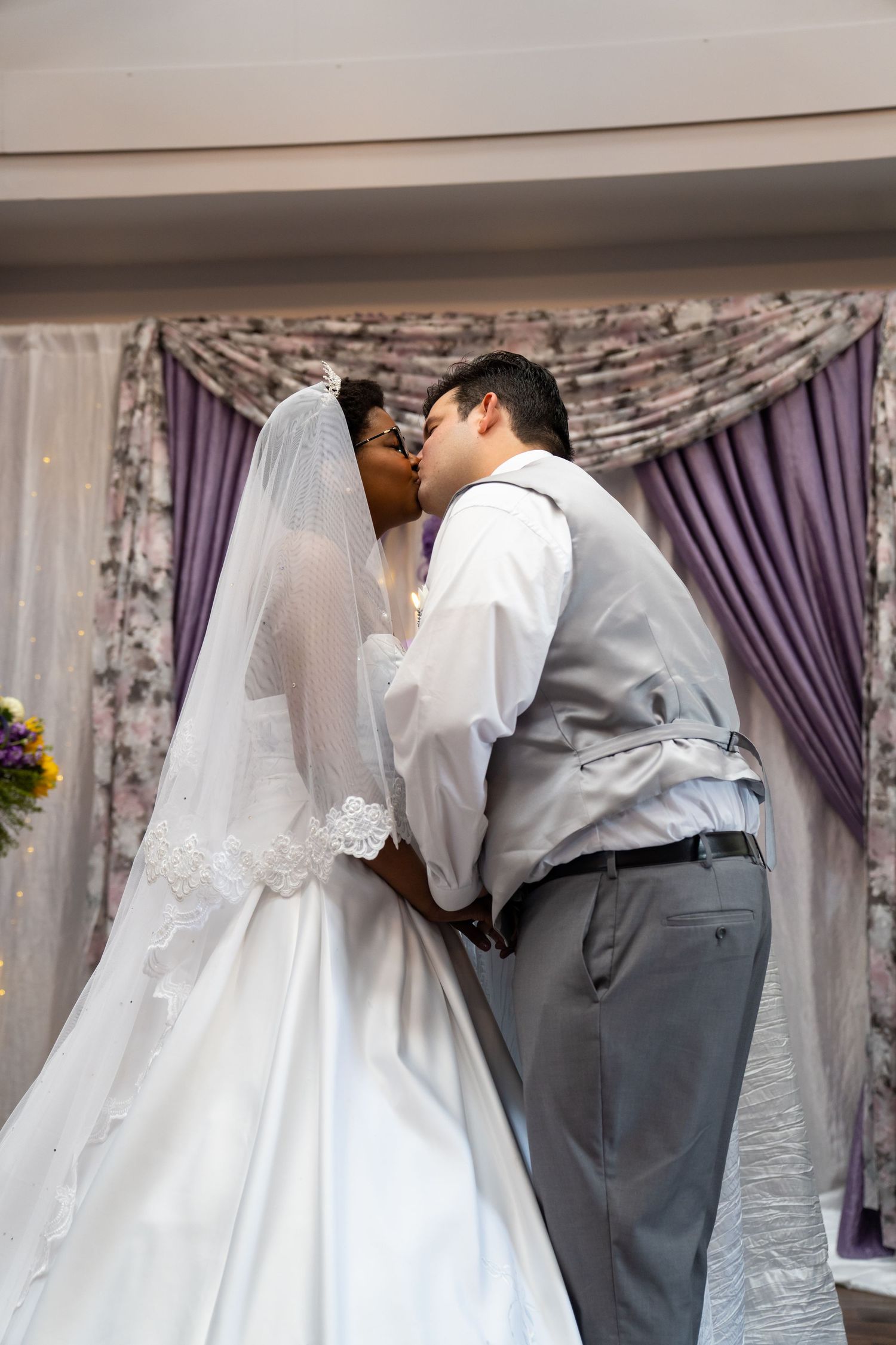A series of wedding photos showing a couple in white dress and gray suit embracing in a room with purple curtains.