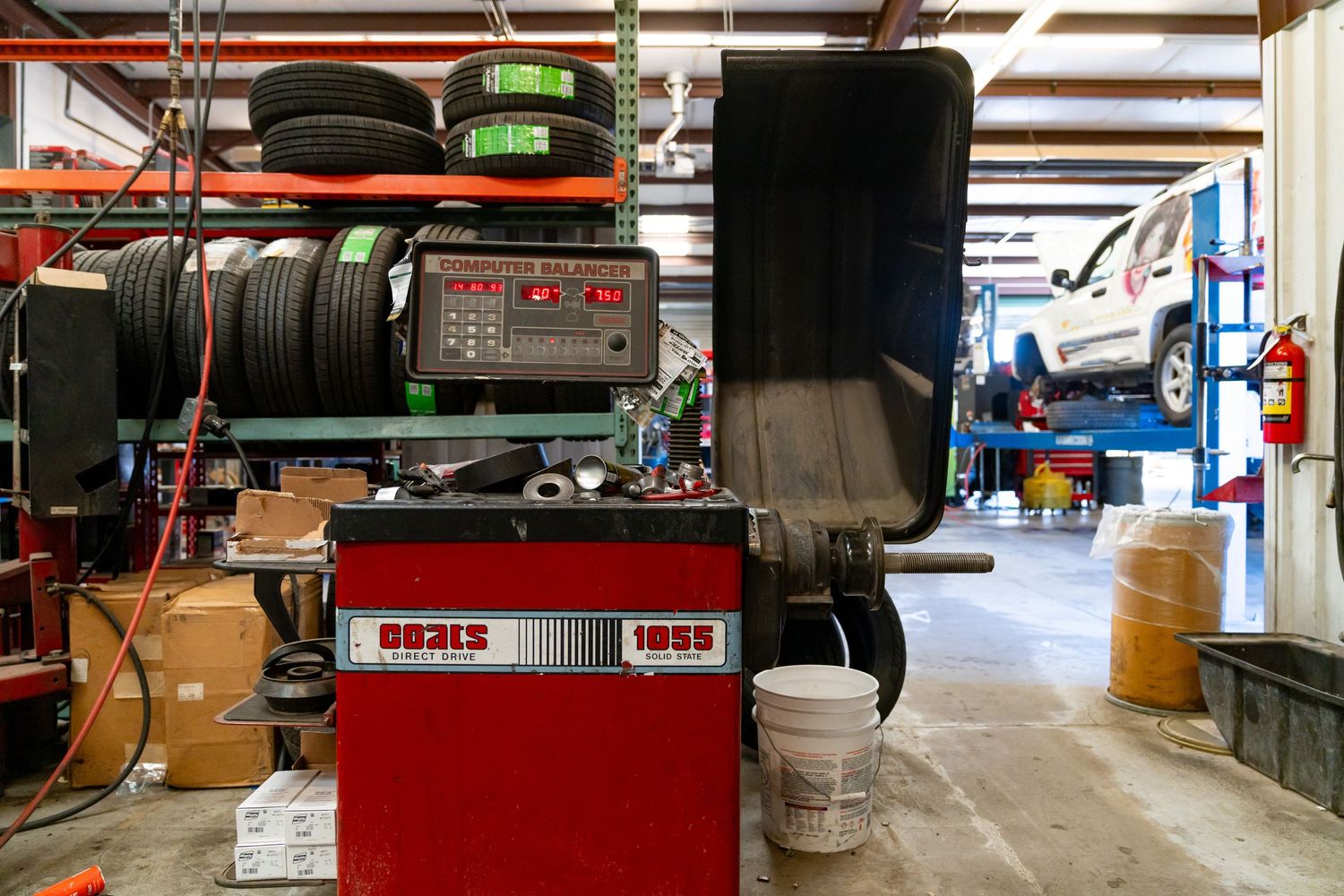 Auto repair shop interior showing red tool cabinets and equipment arranged along the walls of a spacious garage bay.