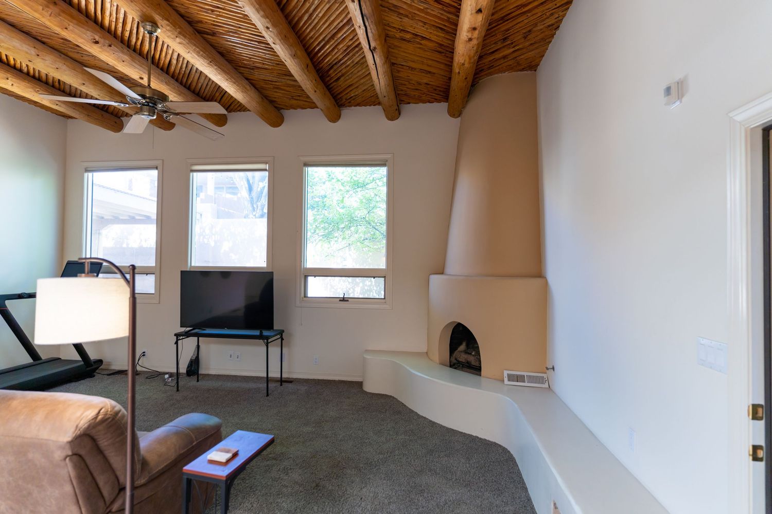 Modern bedroom interior with exposed wooden beams, white walls, and hardwood flooring in a rustic-contemporary style.