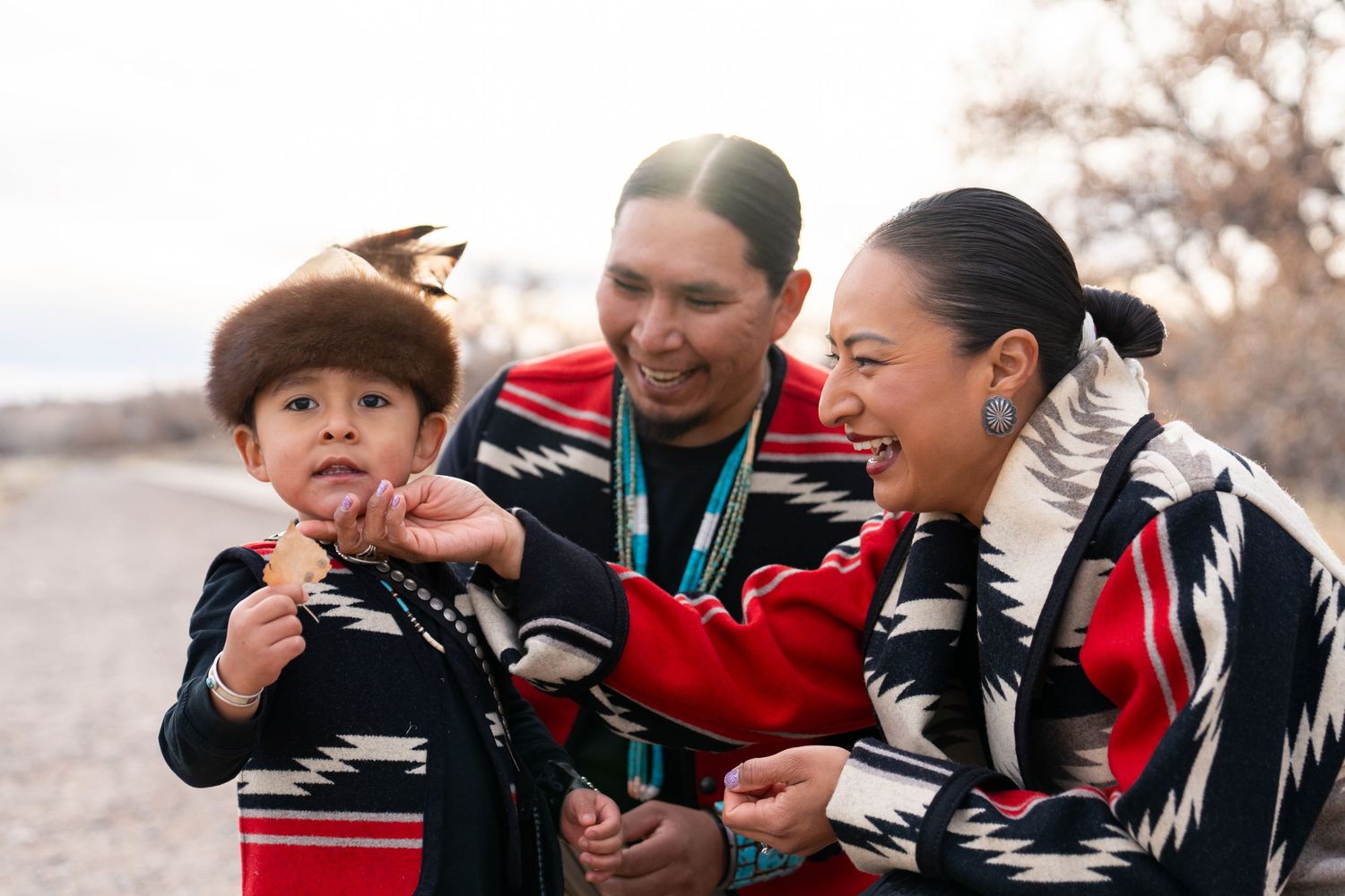Family members sharing joyful moment in traditional Native American attire.