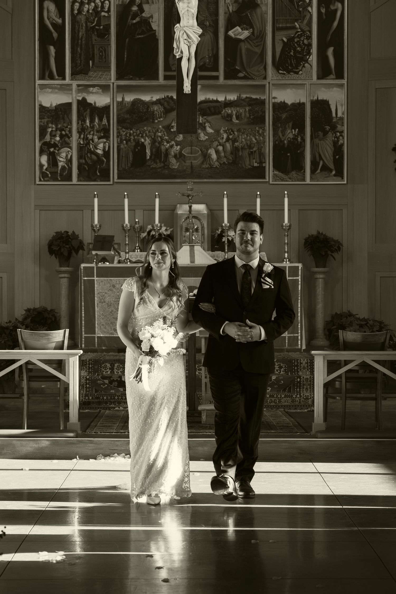 Black and white photo of a church interior with sunlight streaming through windows during a ceremony.