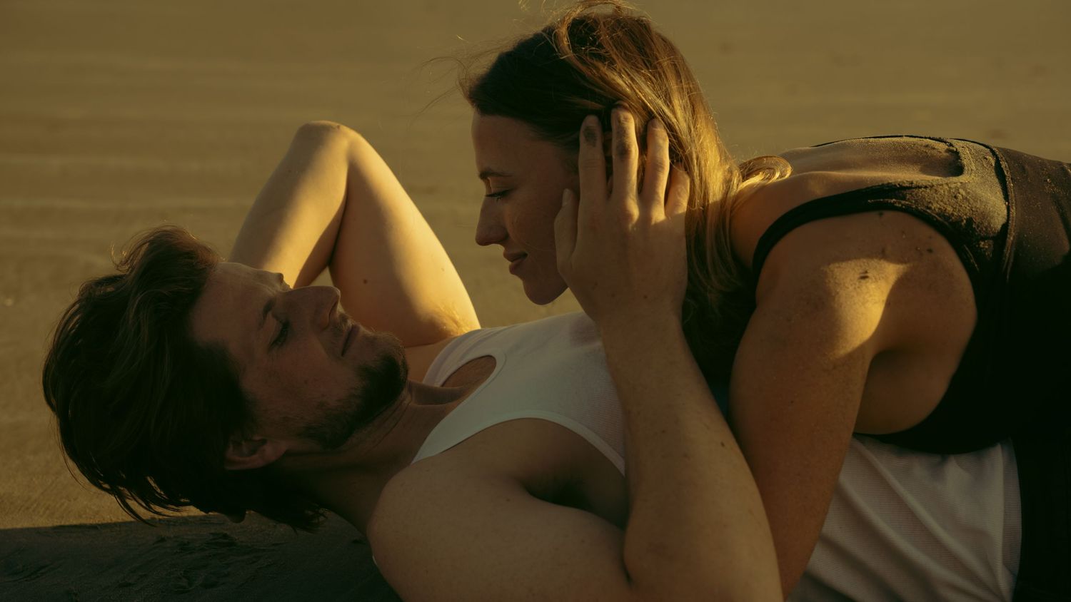 Two people sharing an intimate moment on beach at sunset.