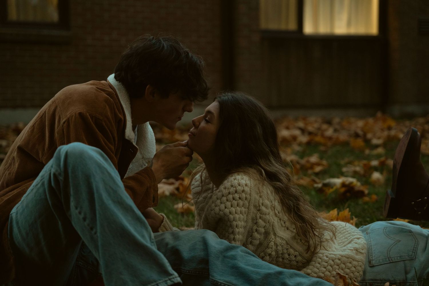 Romantic scene on grass with brick building visible in background.