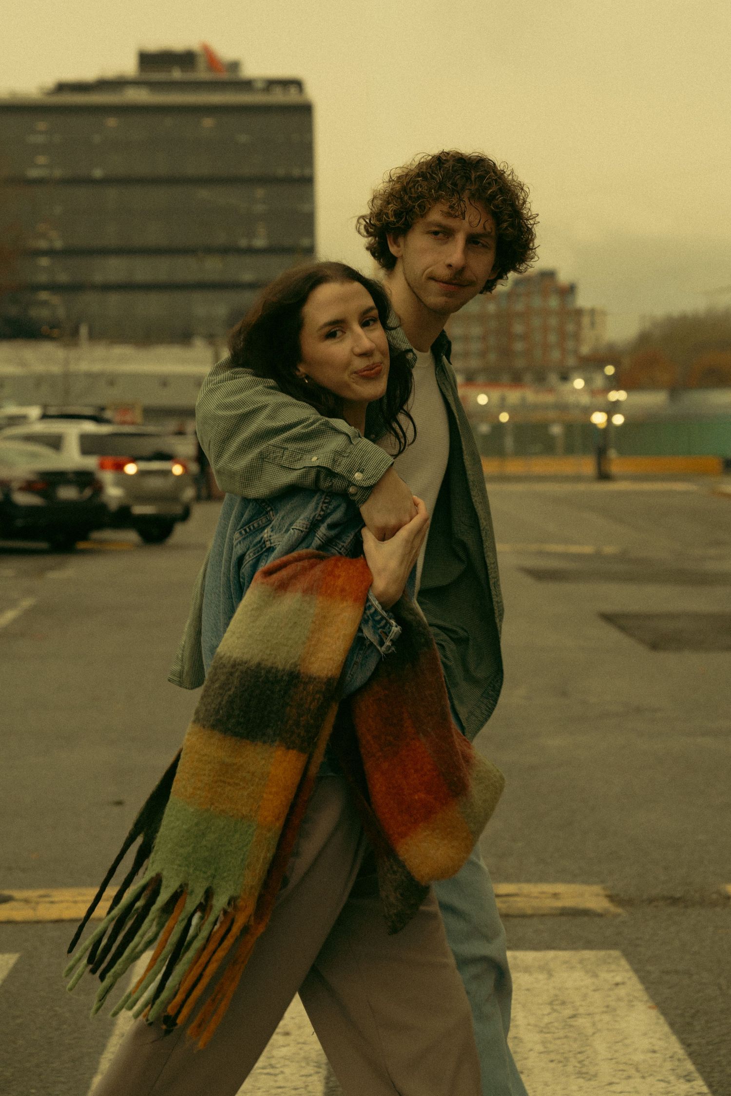 Two people share a romantic moment wearing winter scarves in warm-toned photography.