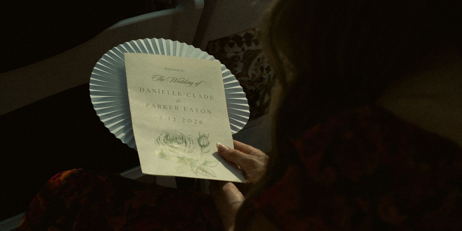 Guest holds decorative wedding program fan with ceremony details at elegant wedding event.