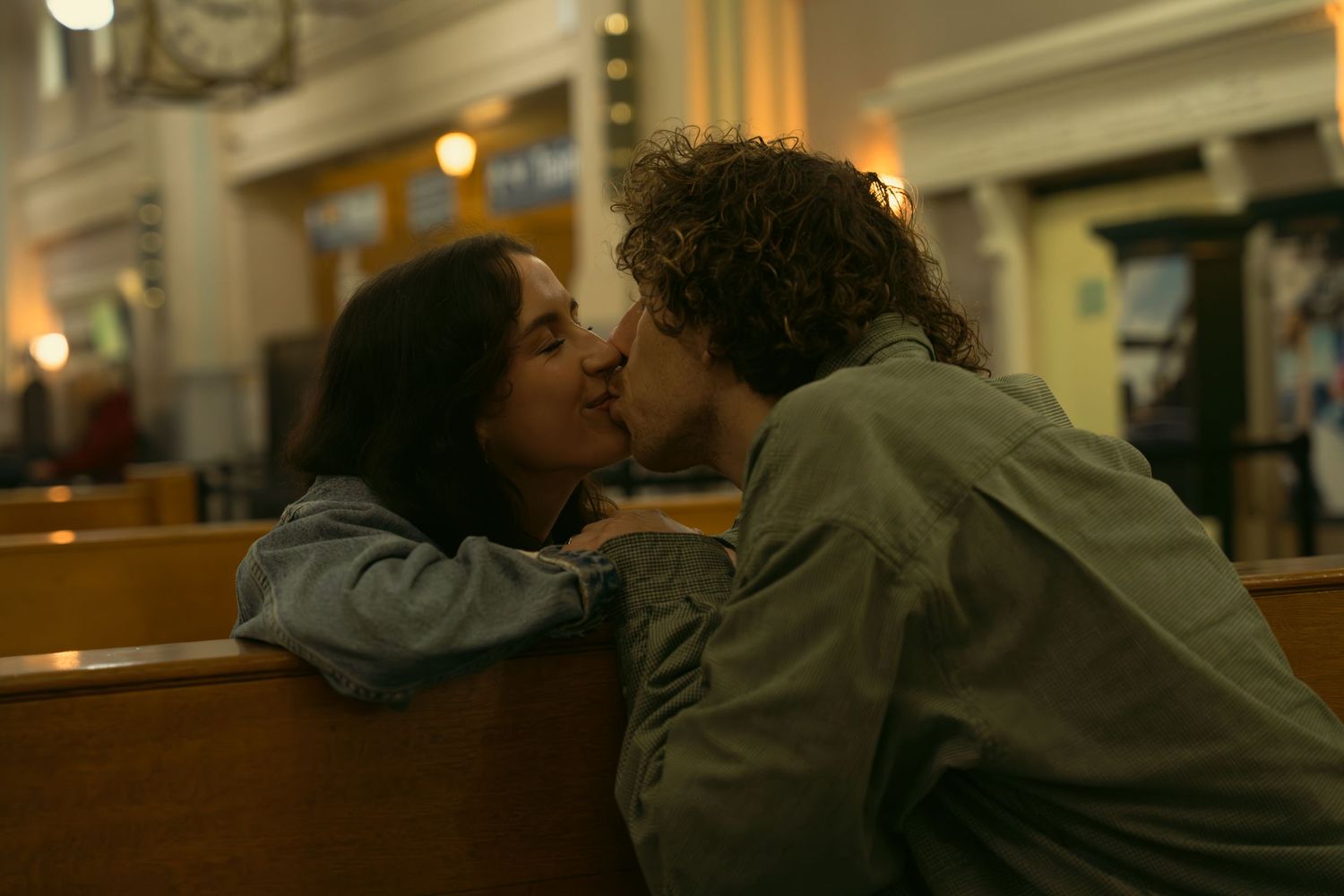 Two people share an intimate moment in warm indoor lighting.