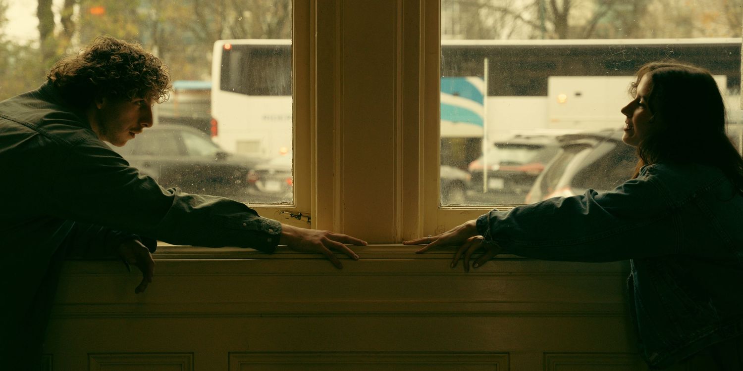 Silhouettes against large windows in a moody interior space with warm lighting.