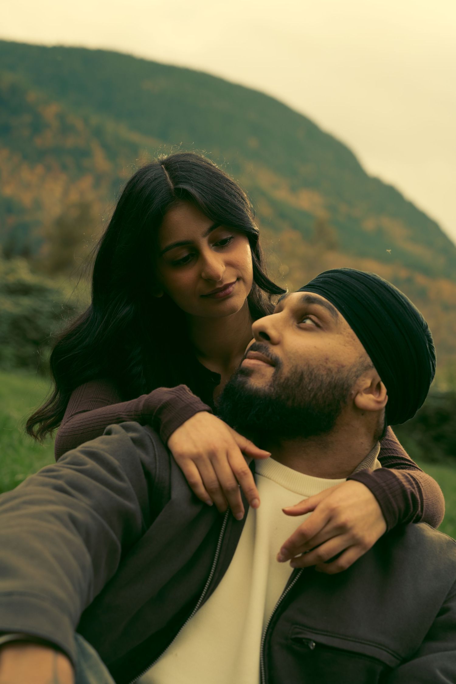 Romantic couple sharing an intimate moment together outdoors with mountains in the background.
