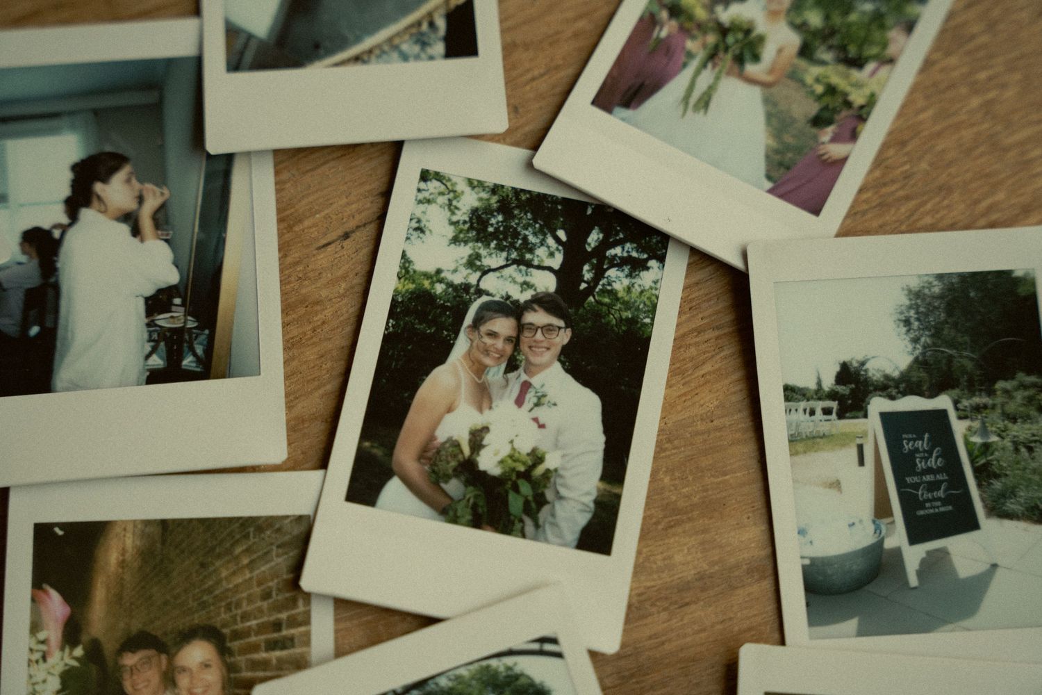 Scattered Polaroid wedding photos on a wooden surface capturing candid moments of a bride and groom.