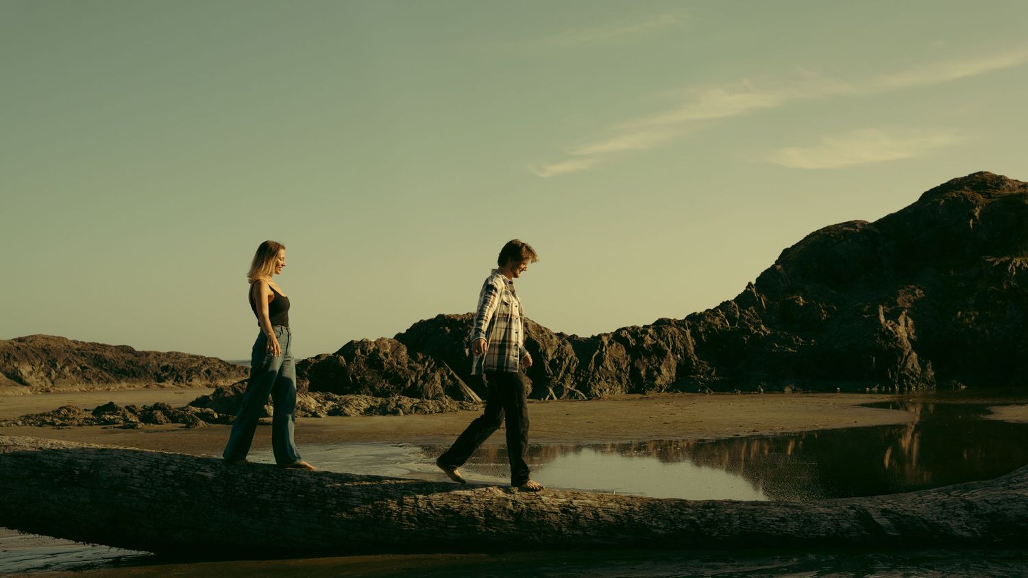 Panoramic desert landscape with figures walking against a warm sky.