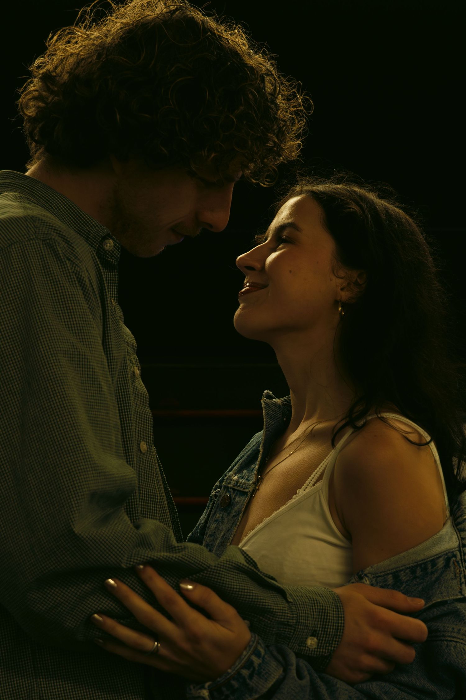 Two figures in an intimate moment captured in dramatic low lighting.