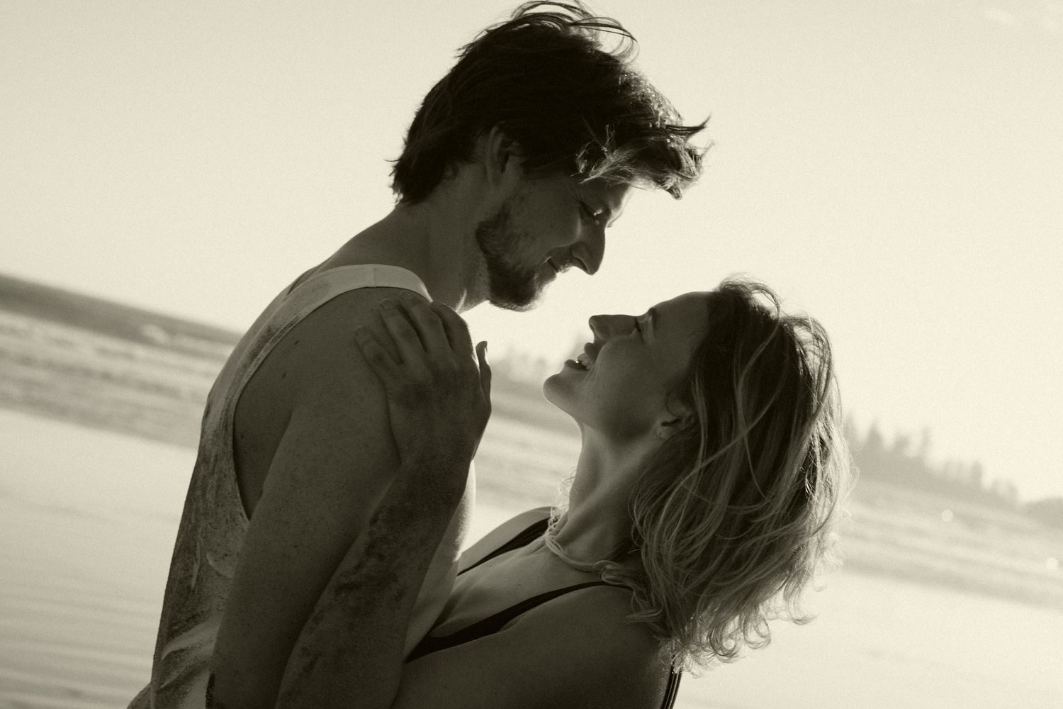Romantic silhouette of couple embracing against sunset at the beach.