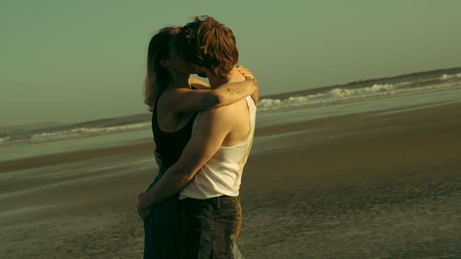 Couple embracing on beach during golden hour.