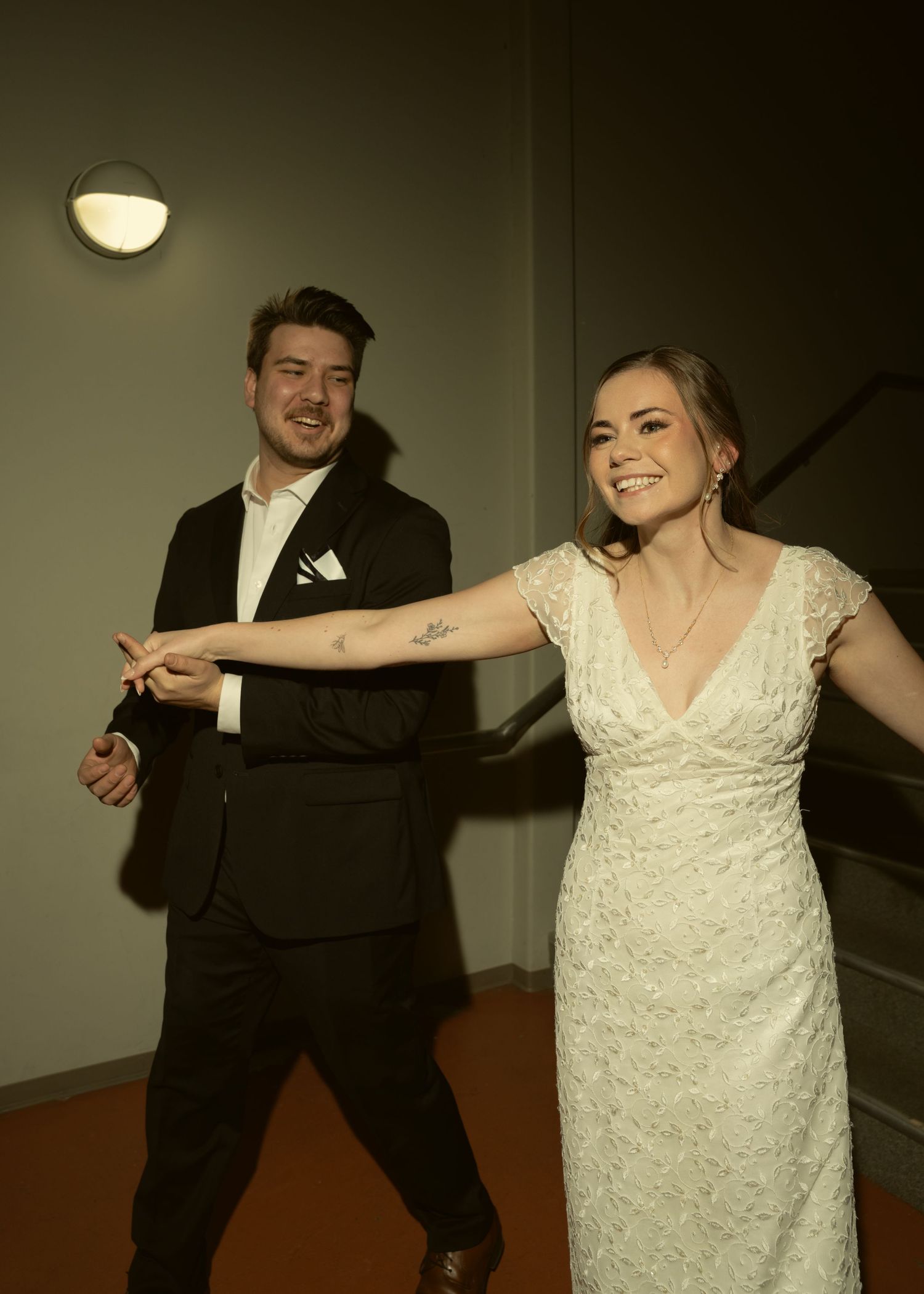 A couple in wedding attire performs a choreographed dance sequence in a dimly lit indoor venue.