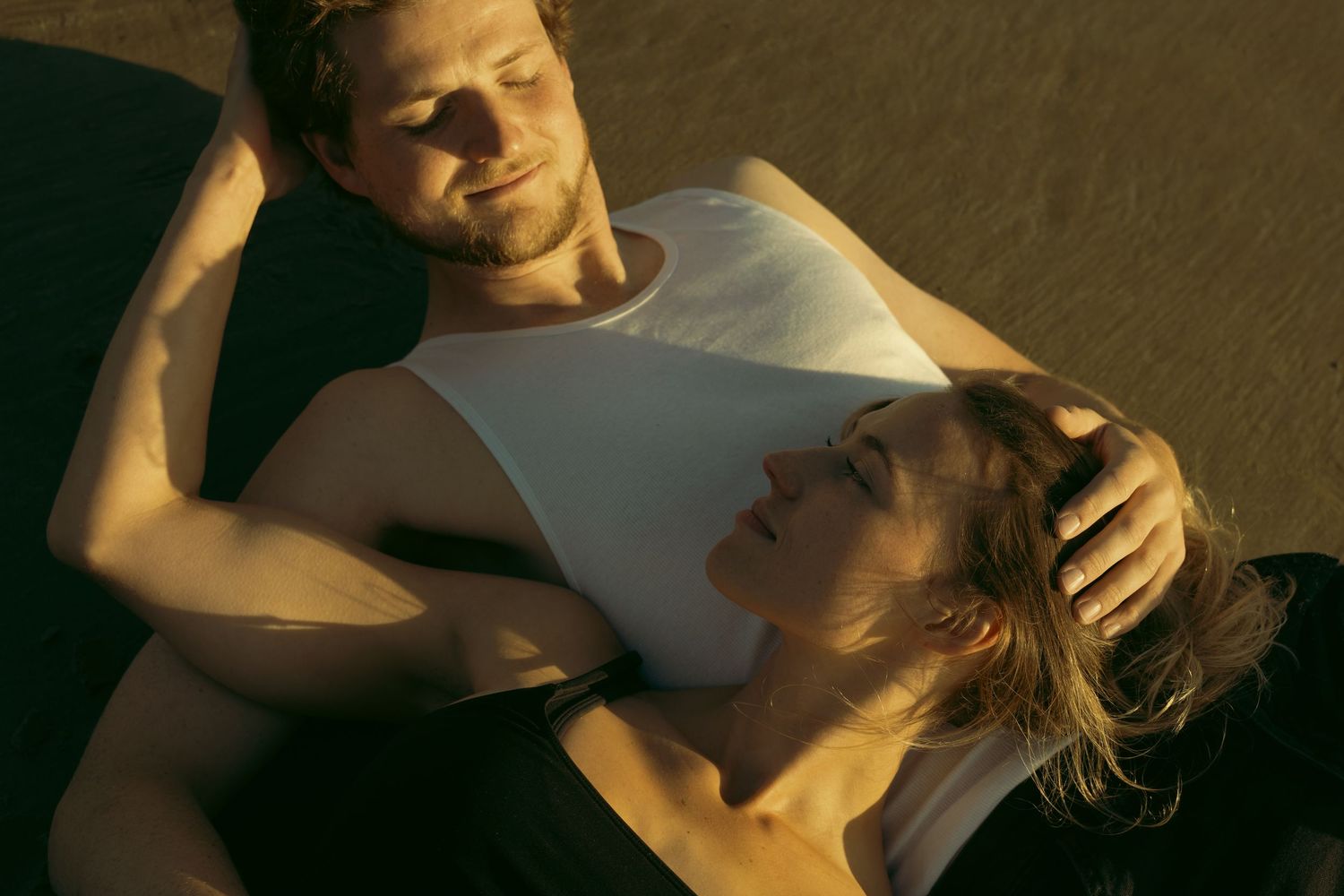 Two people sharing a tender embrace in warm sunset lighting.