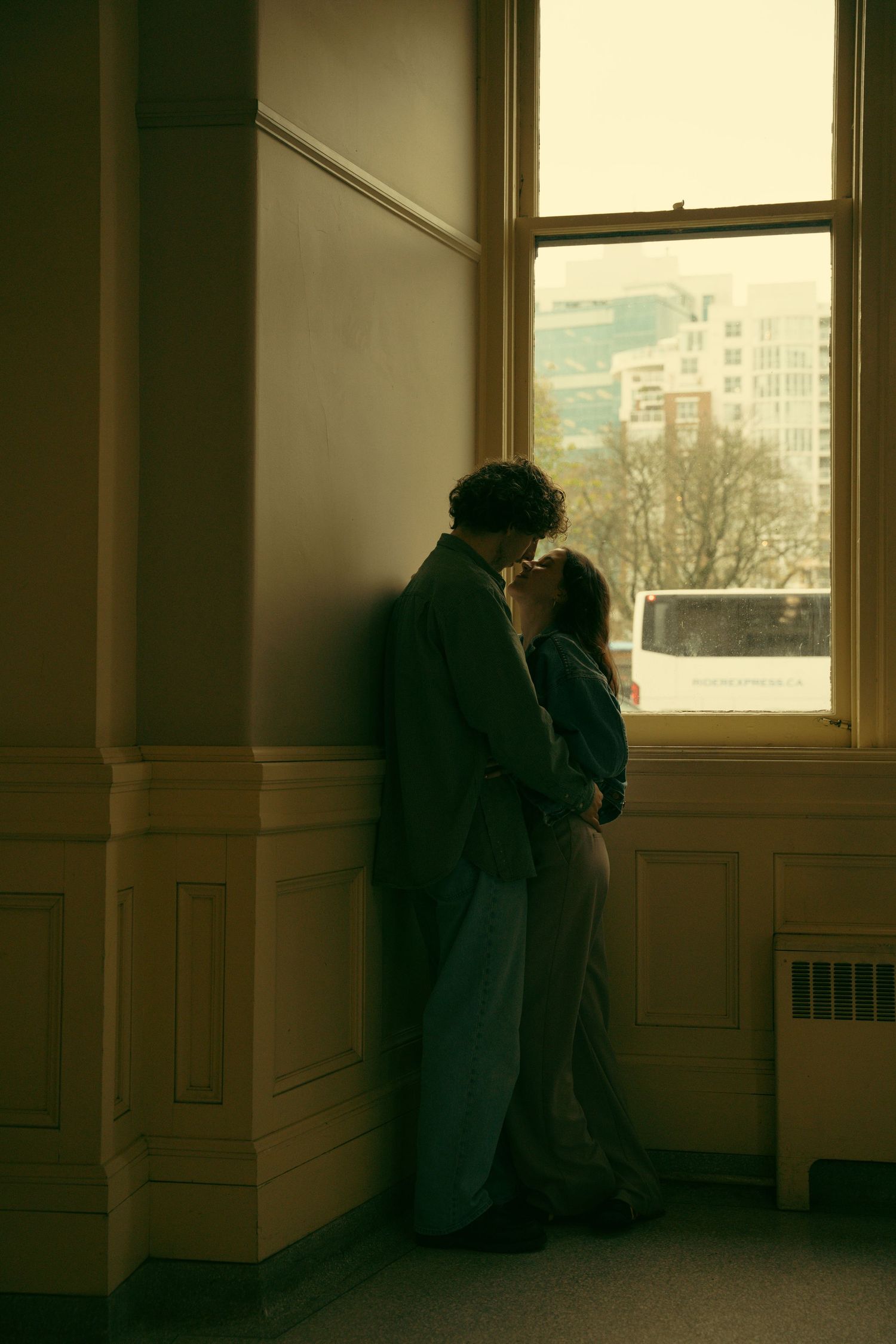 Moody interior shots of a room with large windows and wall paneling.